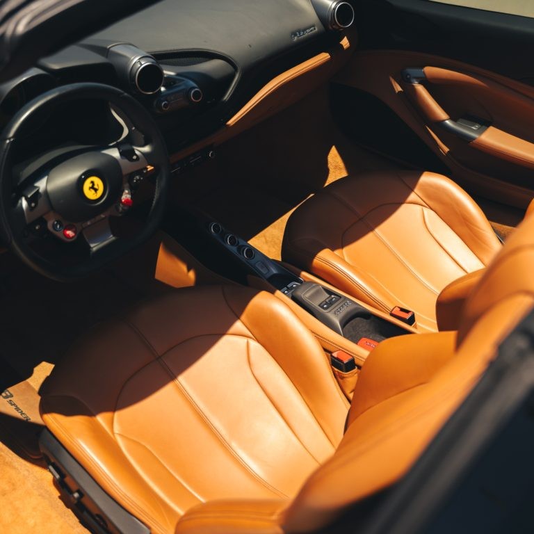 Interior shot of the Ferrari F8 Spyder's luxurious tan leather seats and driver-focused cockpit.
