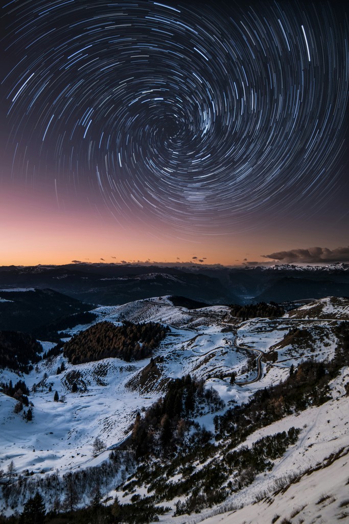 Star trails above a snowy mountain at night