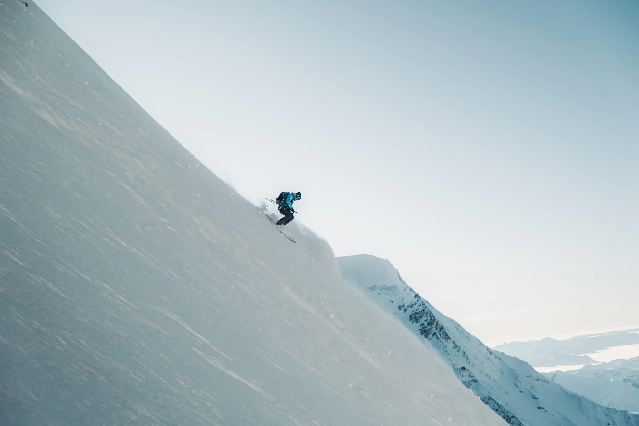 Vignette Alpiniste descendant une paroi enneigée avec baudrier et piolets, équipement Millet.