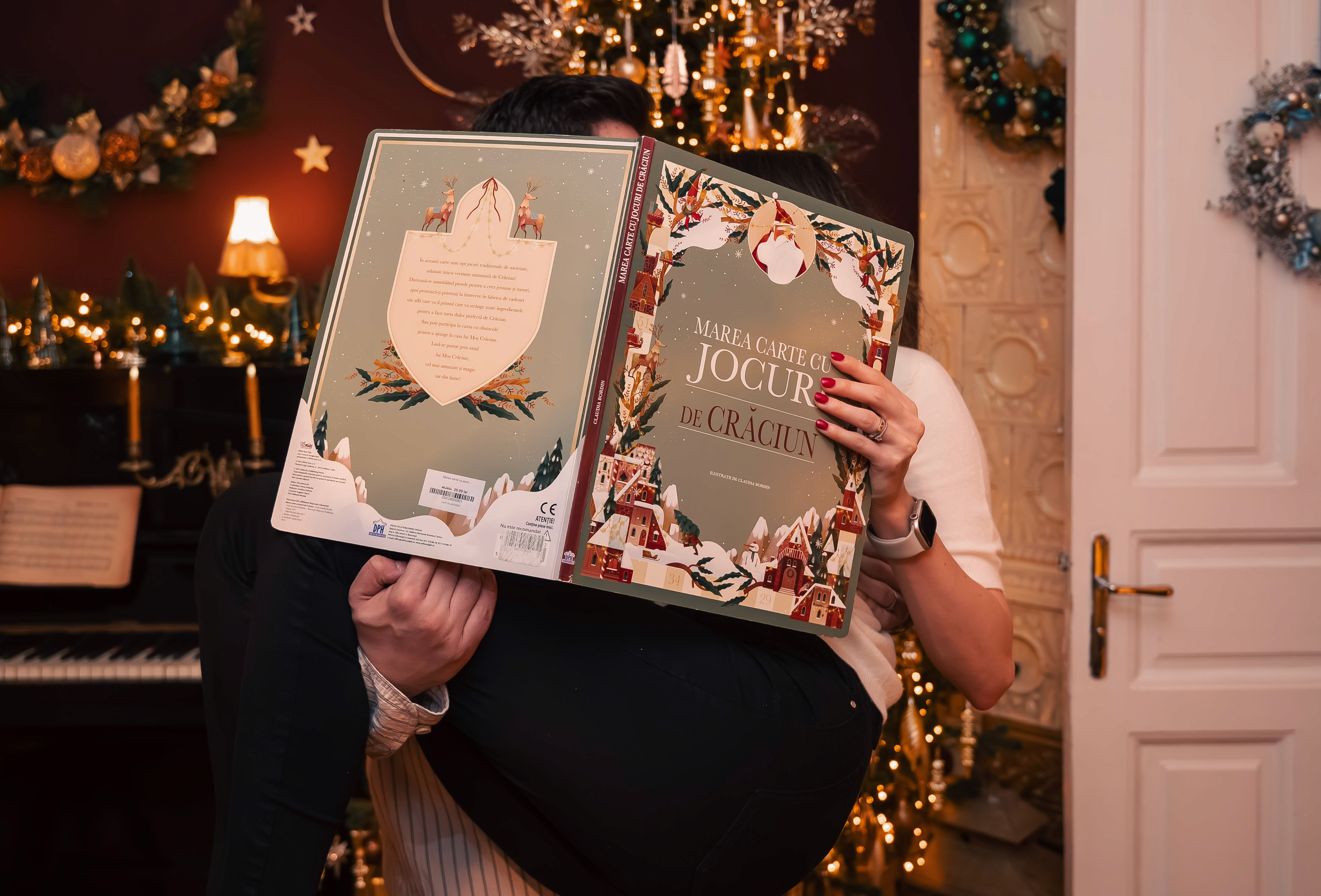 Fotografii de Crăciun cu persoană ascunsă după cadouri, moment jucăuș și decor festiv