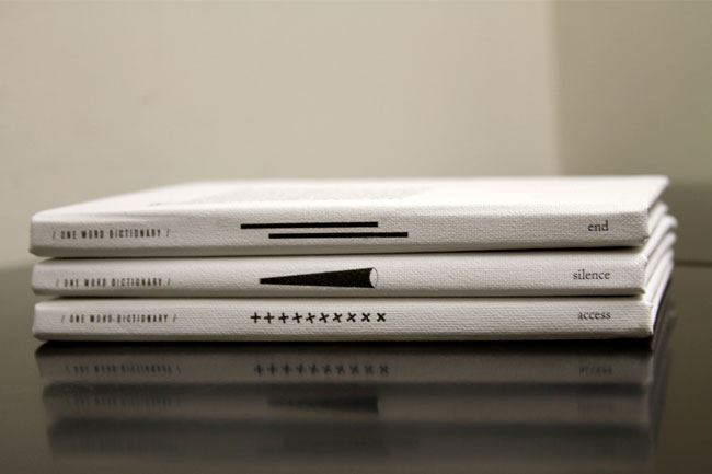 Three white books are stacked on a dark reflective surface. The top book is titled “end,” the second is “silence,” and the third is “access.” Each book has a black horizontal line near the top edge and a black arrow pointing toward the bottom right corner. The titles and line patterns are printed in black ink. The books are arranged neatly, and the reflective surface shows faint reflections.