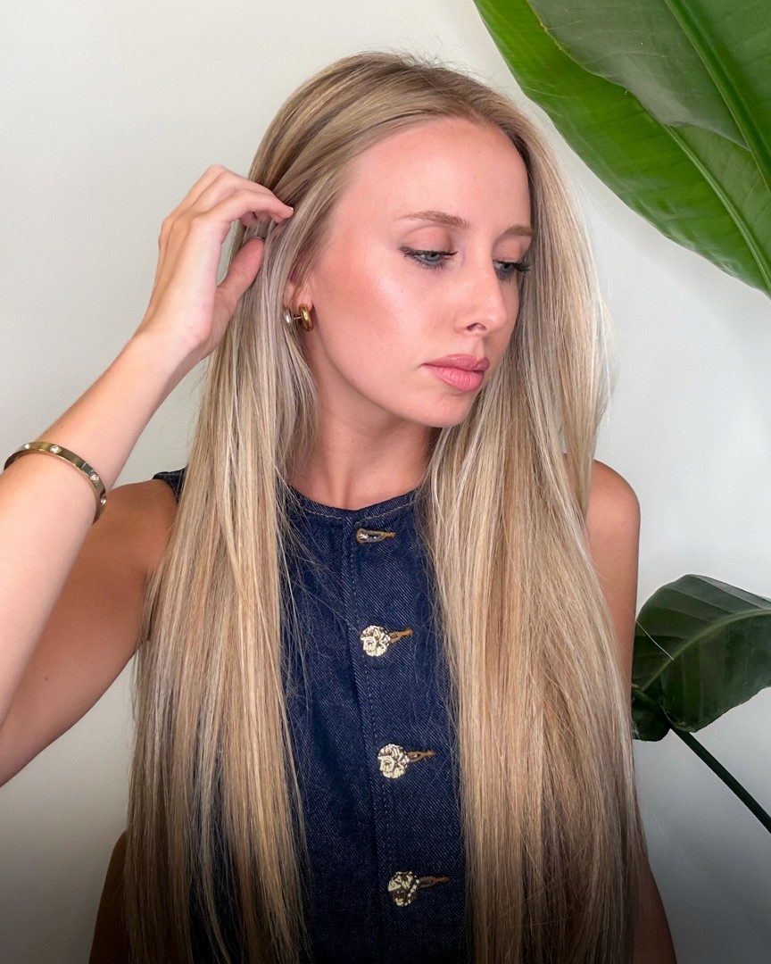 A woman lying on a massage bed, illuminated by soft sunlight streaming through a nearby window. A lush green plant in the background enhances the peaceful and rejuvenating ambiance.