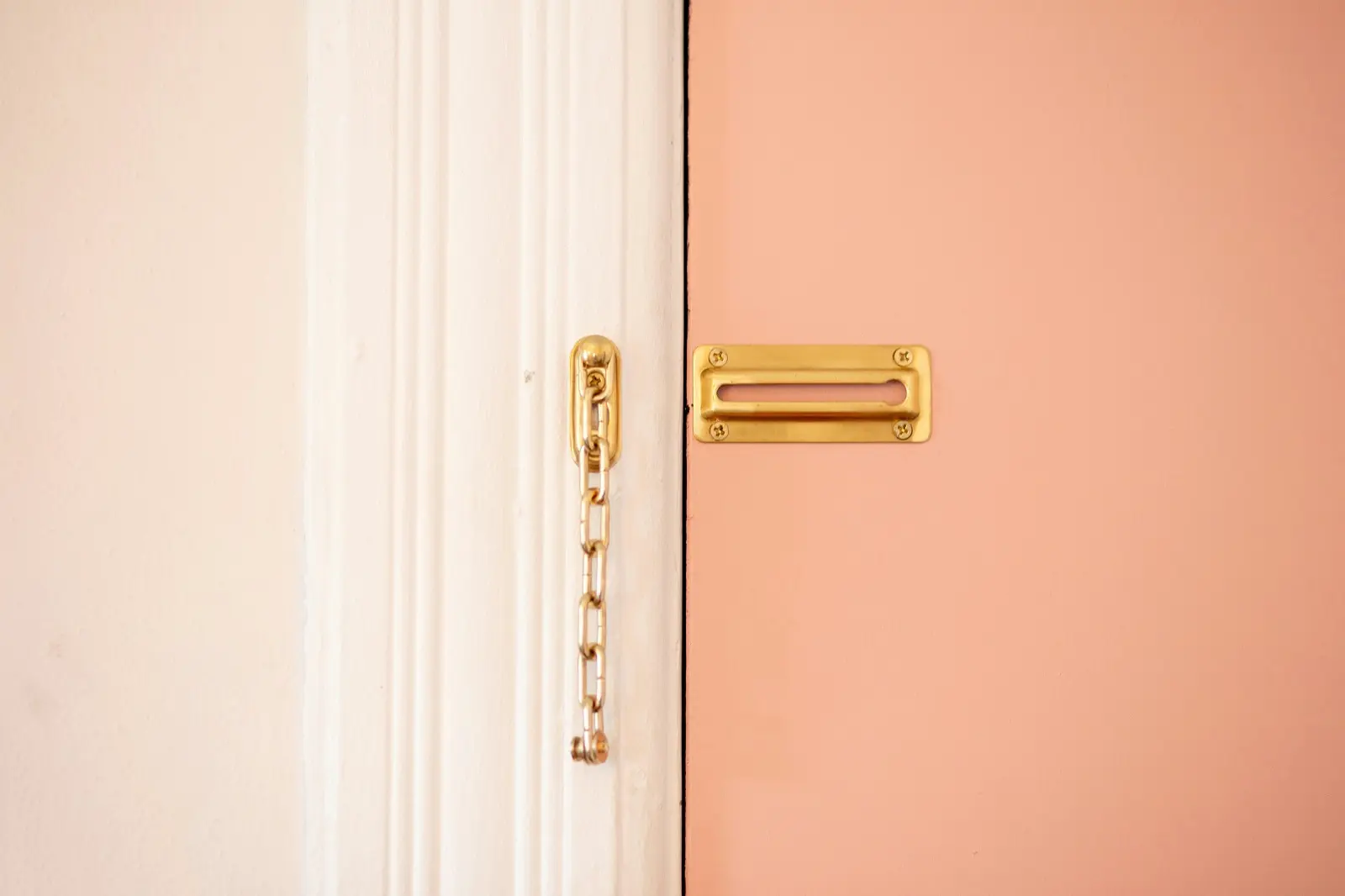 Minimal doorway detail showing a locked chain and mail slot on a closed door
