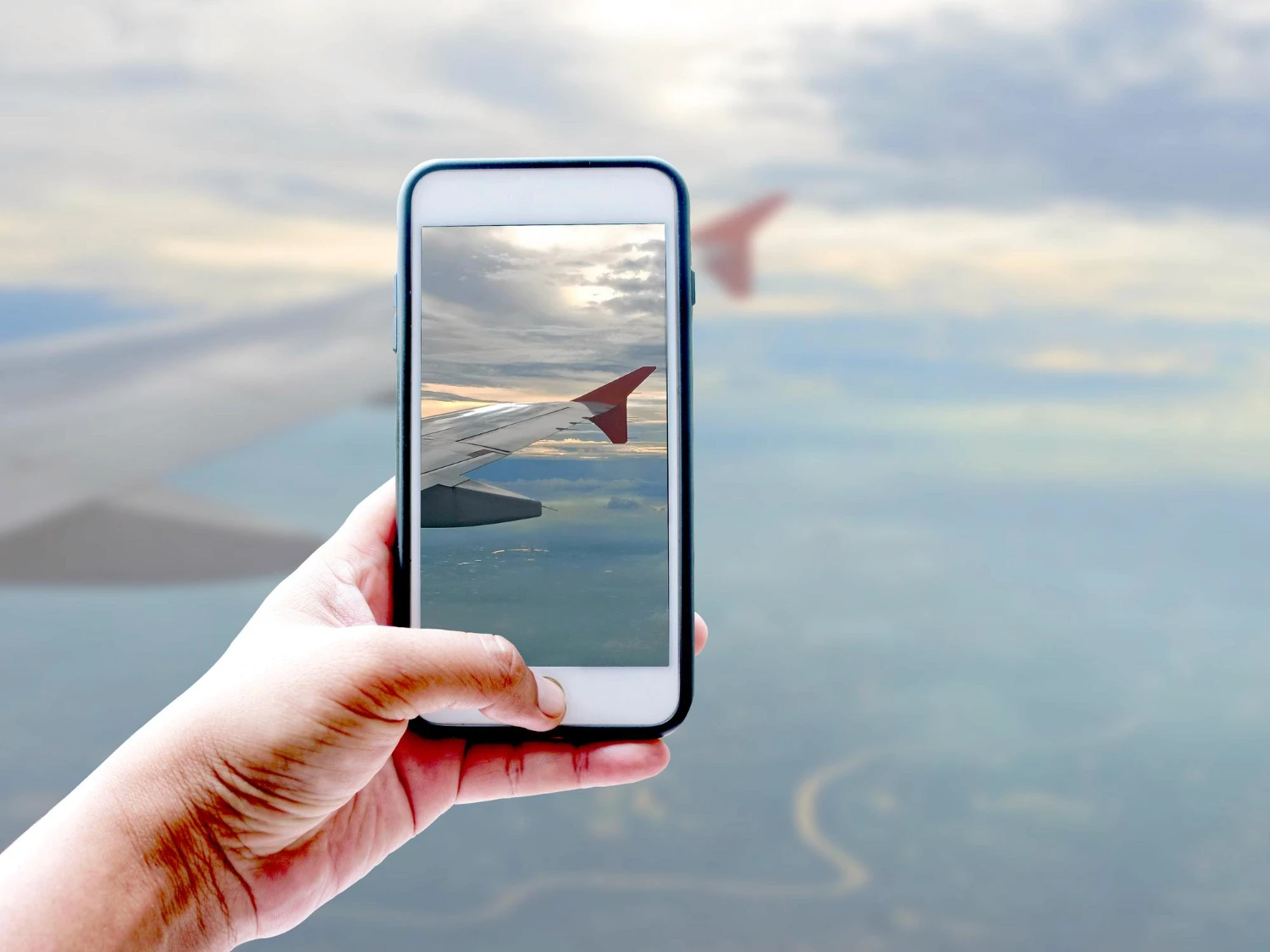 hand holding a phone taking a photo of a plane