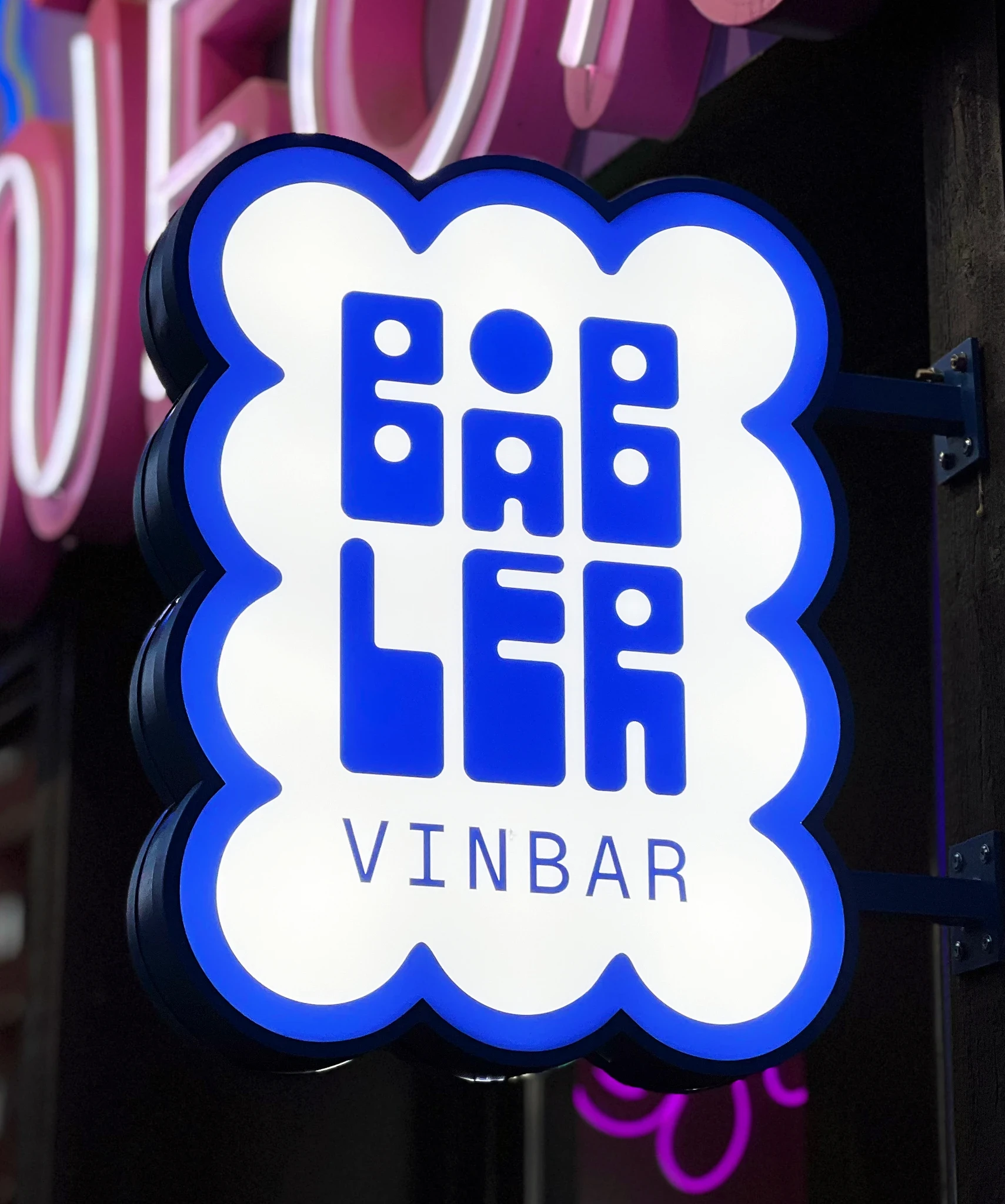 A bright lit custom wall sign with Båbler's logo shining in the dark.