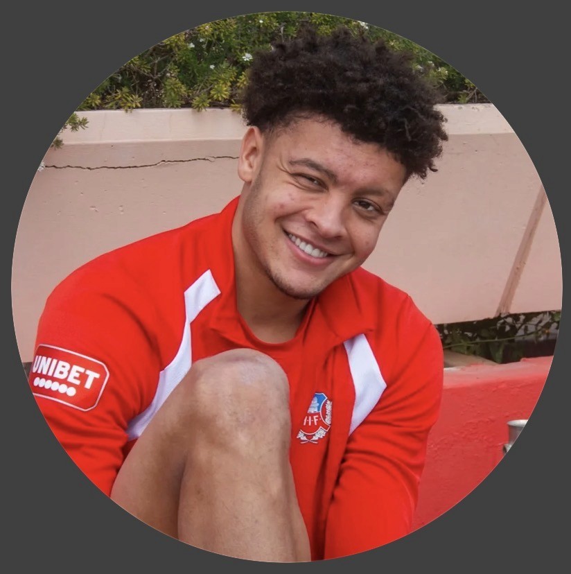 Young woman with long brown hair wearing large headphones and a beige coat stands in an autumn forest, evoking a serene, contemplative mood.