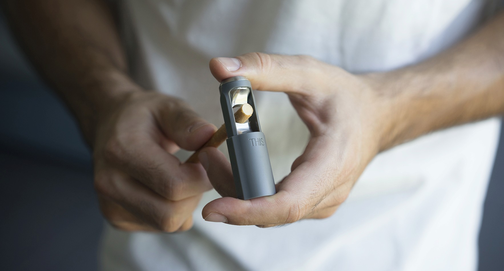 A photo of a man cutting a stick with a cigar cutter.