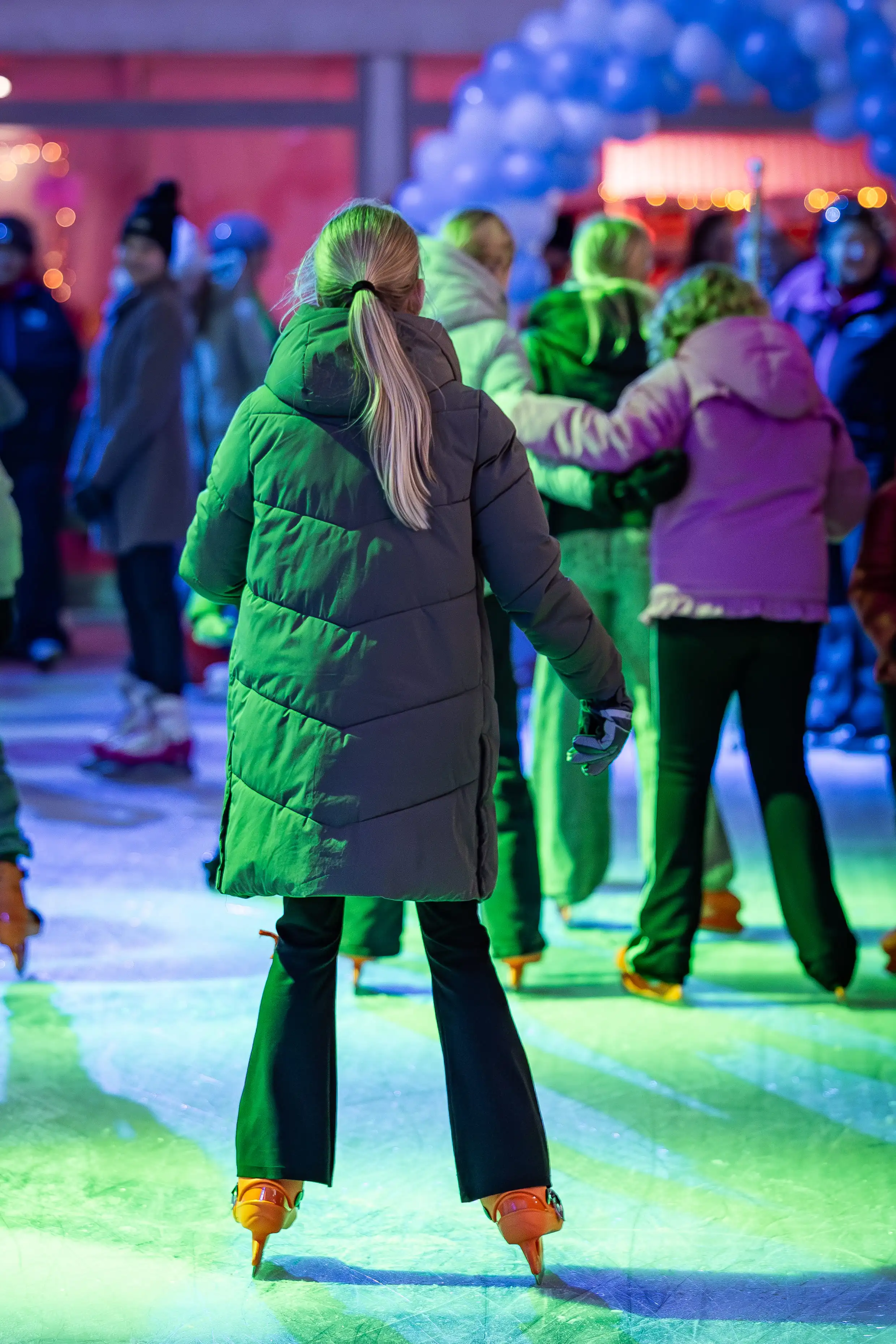 Schaatsers op de verlichte ijsbaan in de avond