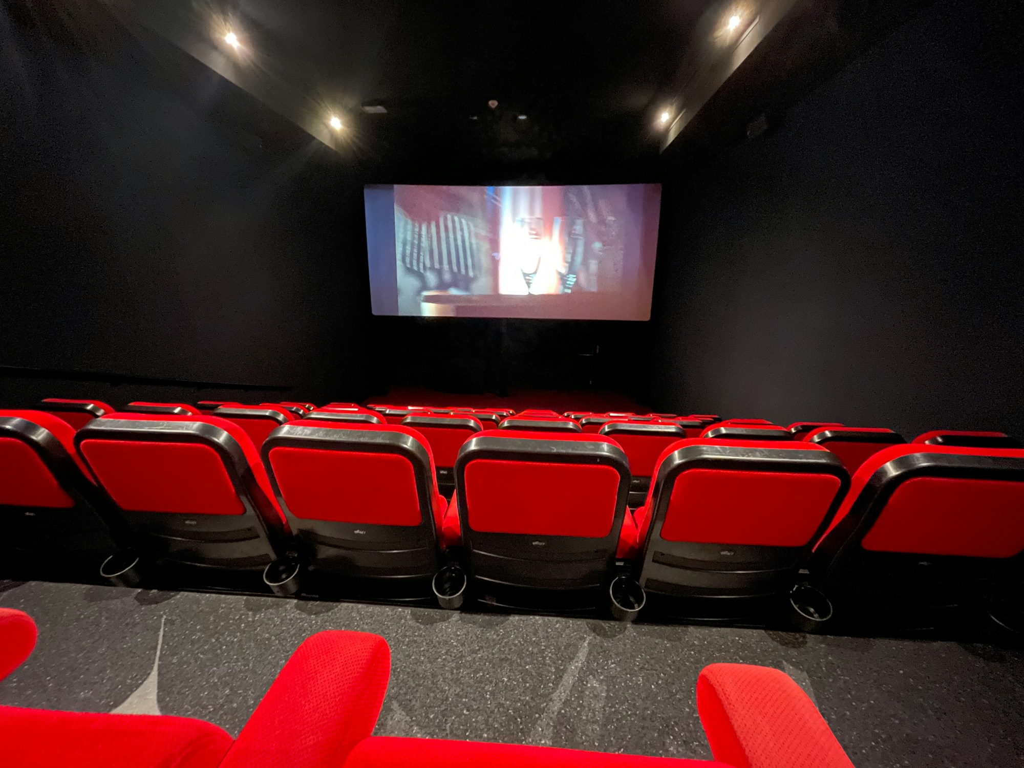 Rows of red seats facing the screen in a small cinema