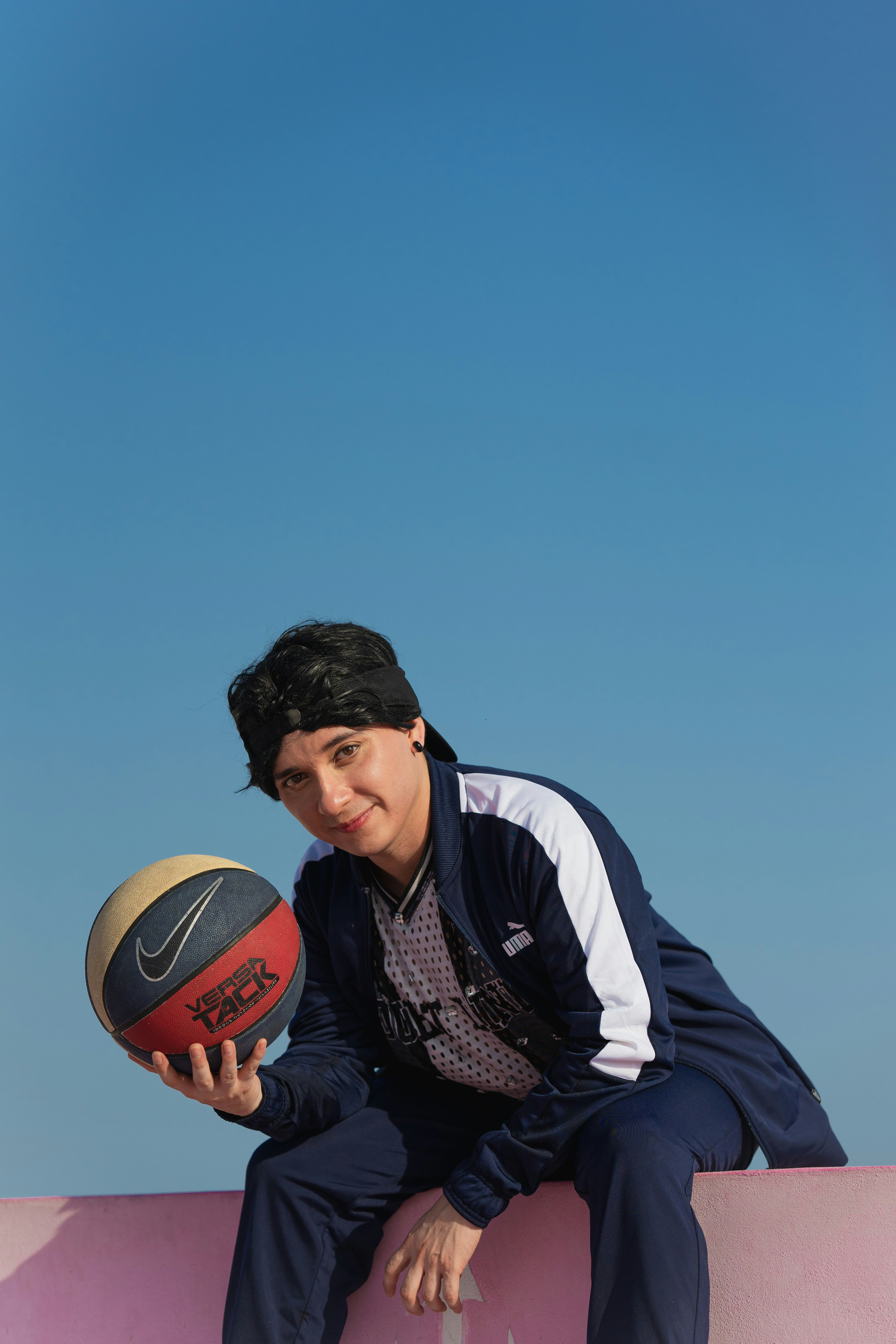 A man sitting on a wall holding a basketball