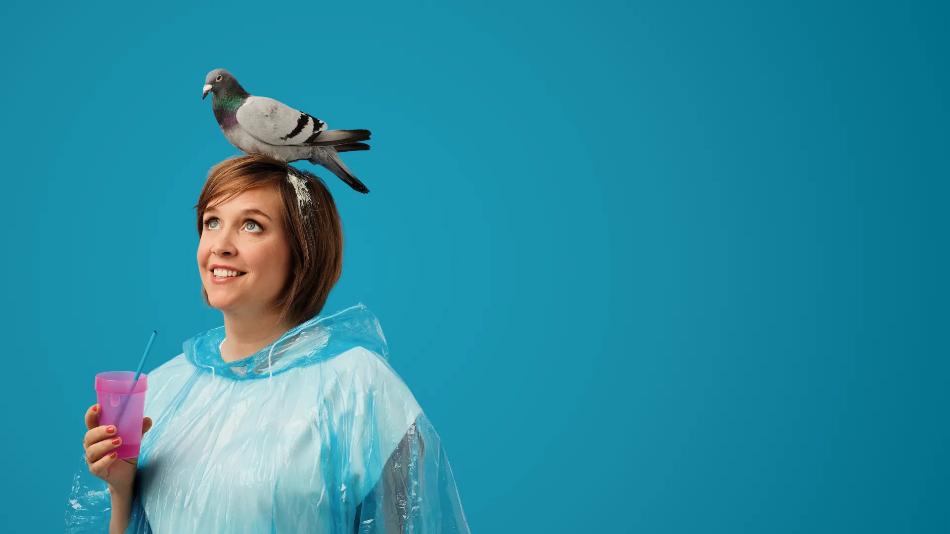 Manon Lepomme en poncho de pluie, un gobelet rose à la main et un pigeon sur la tête