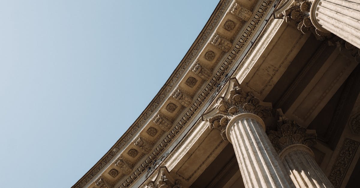 Detailed low-angle view of classical columns against a clear sky reflecting historical architectural