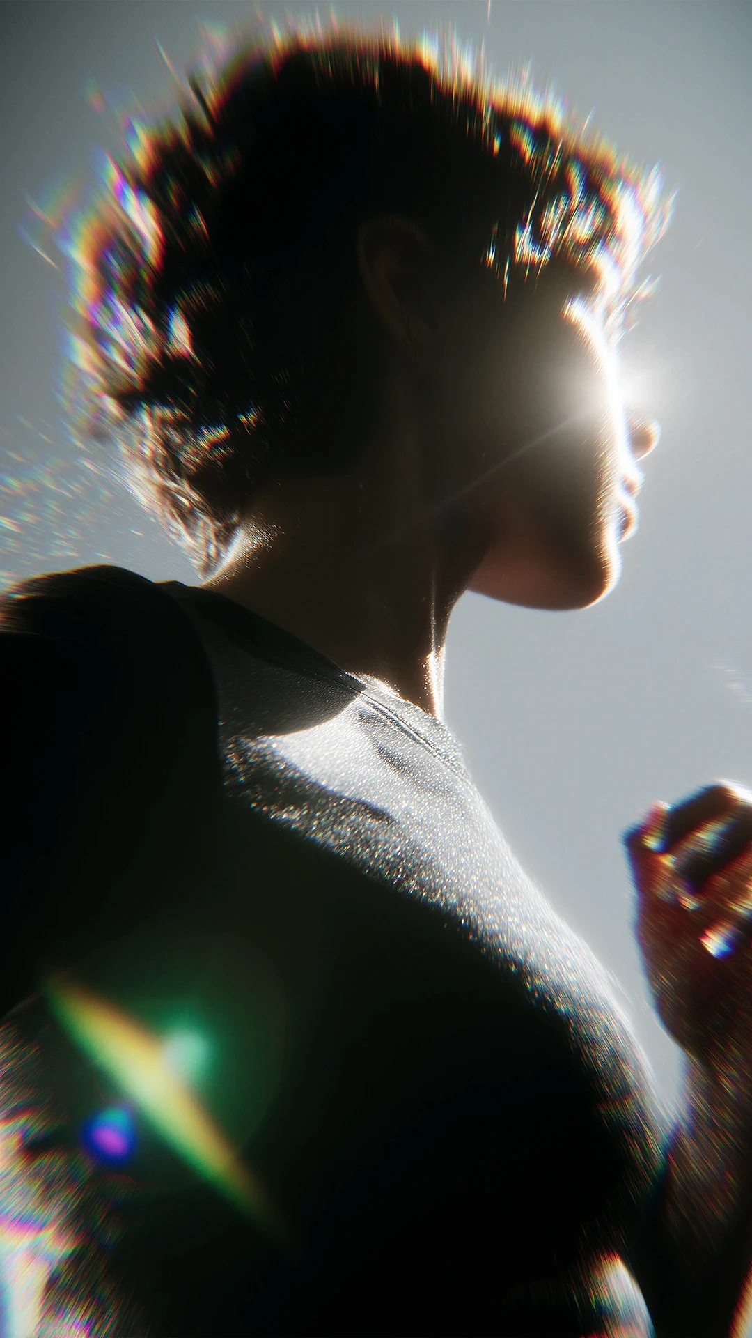 Artistic side profile of a person with short hair, dramatic lighting, lens flare and vibrant rainbow diffraction effects.