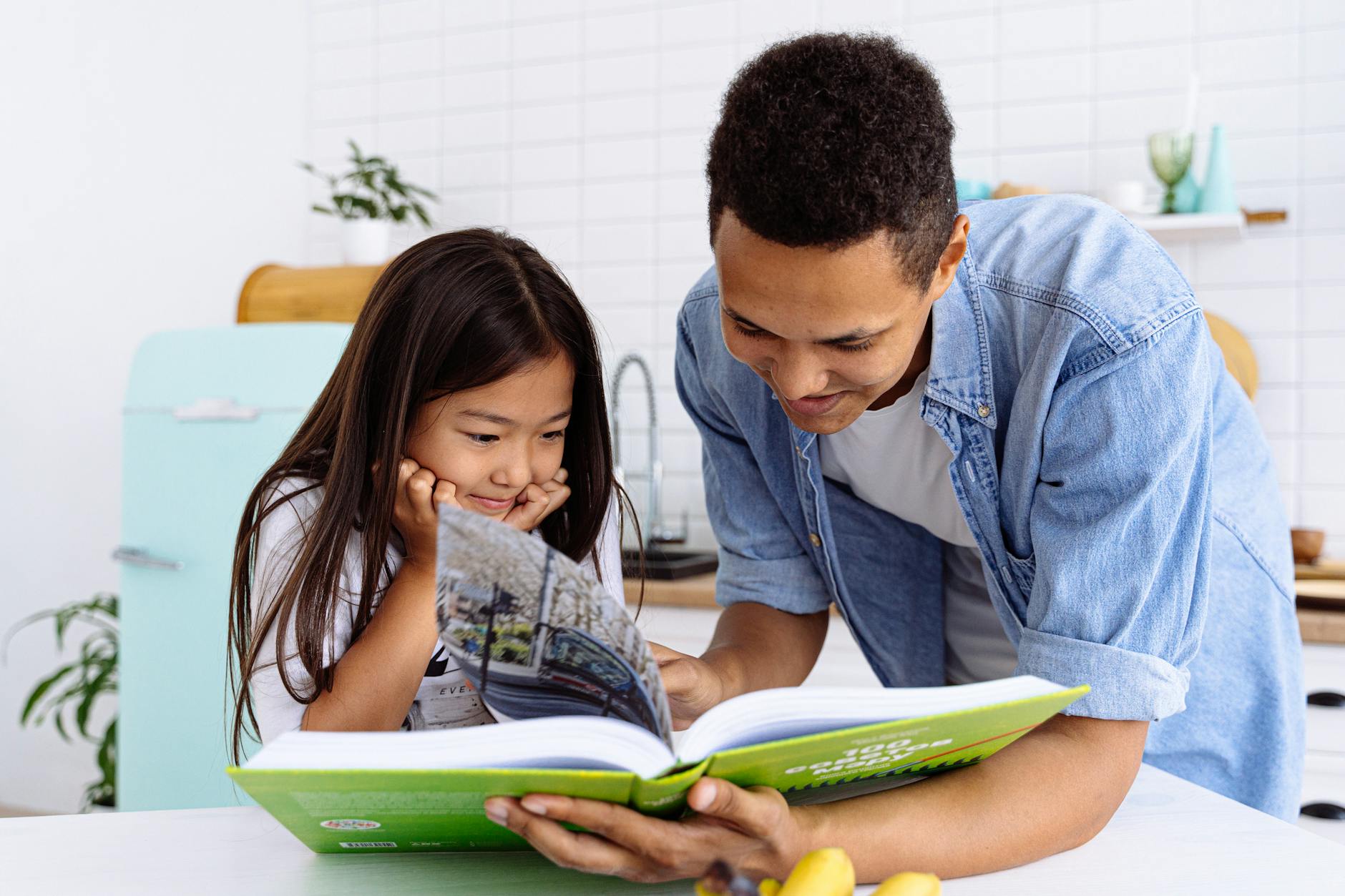 Two smiling children wearing backpacks and holding a 'First Day of School' sign in their living room.