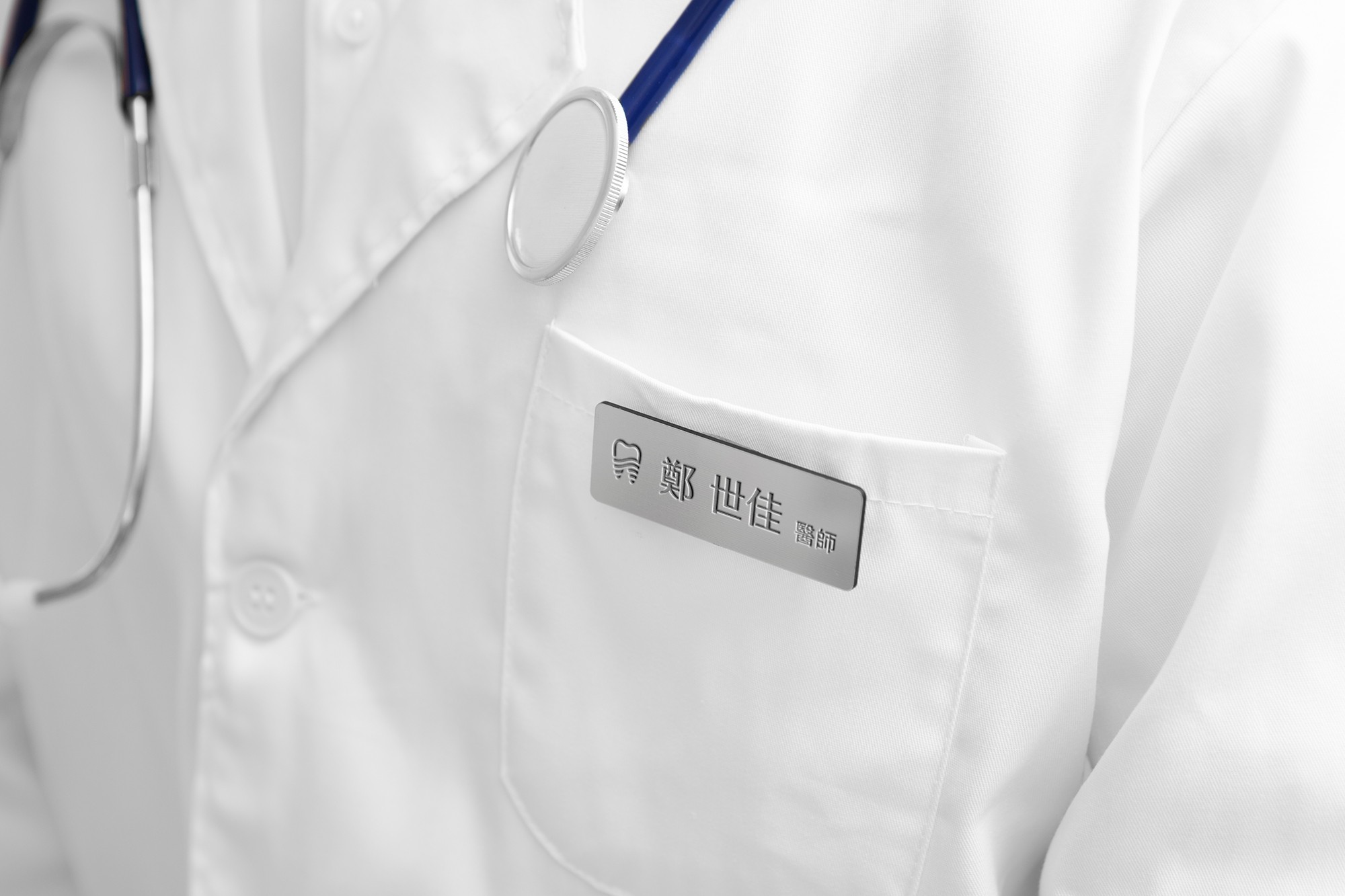 這張圖像展示了東樂牙醫診所的醫師識別胸章,胸章上有牙齒圖案標誌和醫生的名字。