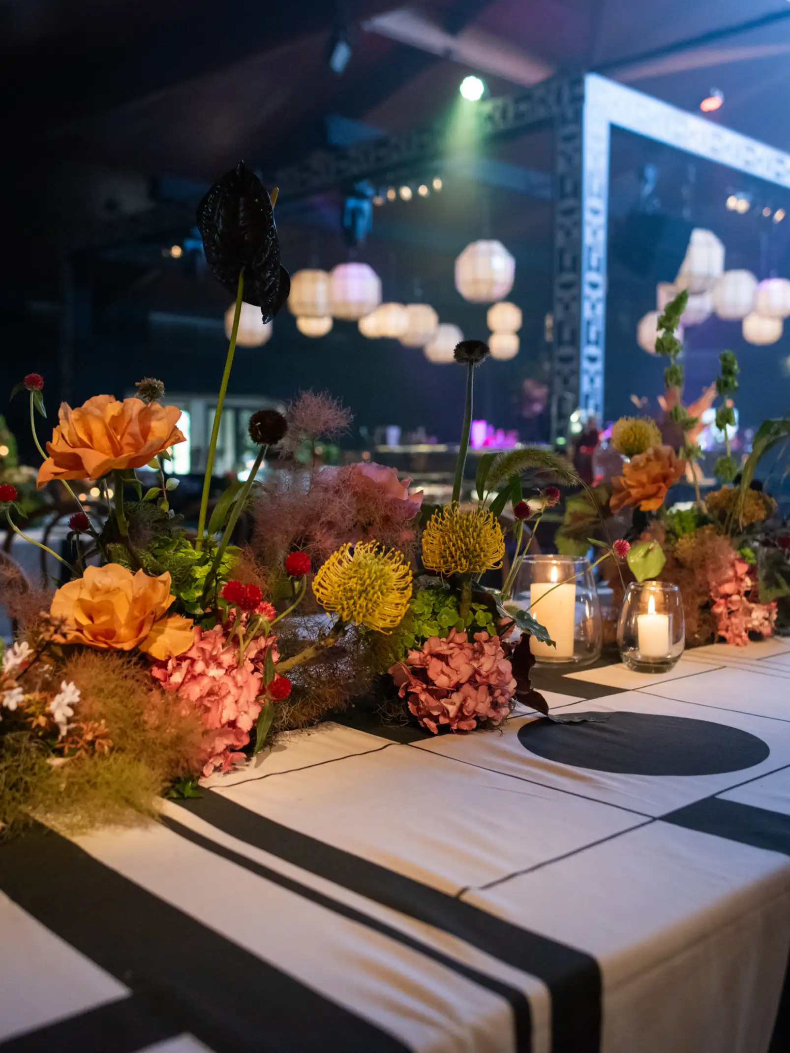 Decoración de mesa con arreglos florales en tonos cálidos, velas y manteles con diseño geométrico.