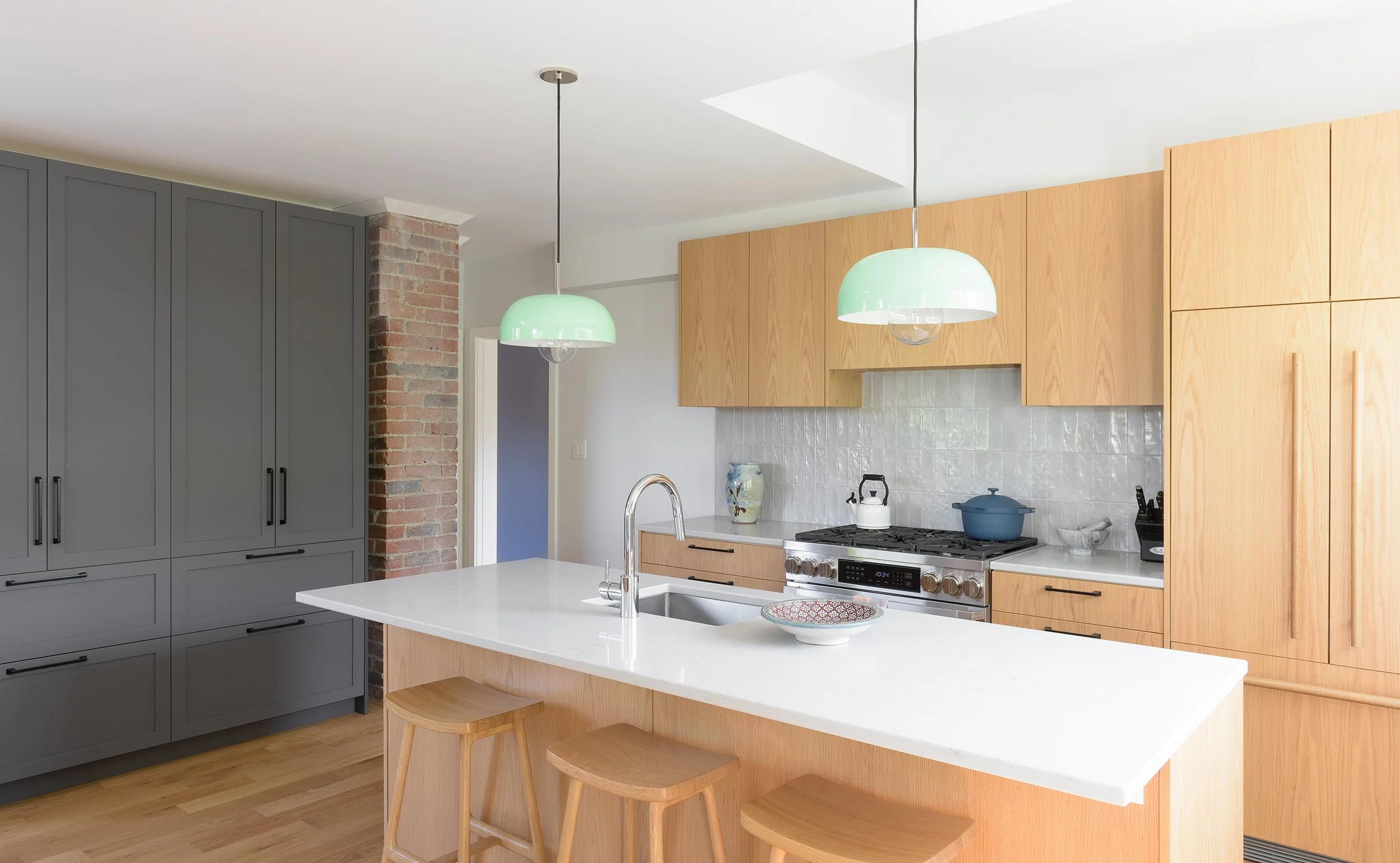 Modern two-story home with large glass windows, warmly lit interiors, and a balcony. Surrounded by trees and a manicured lawn at dusk. Cozy ambiance.