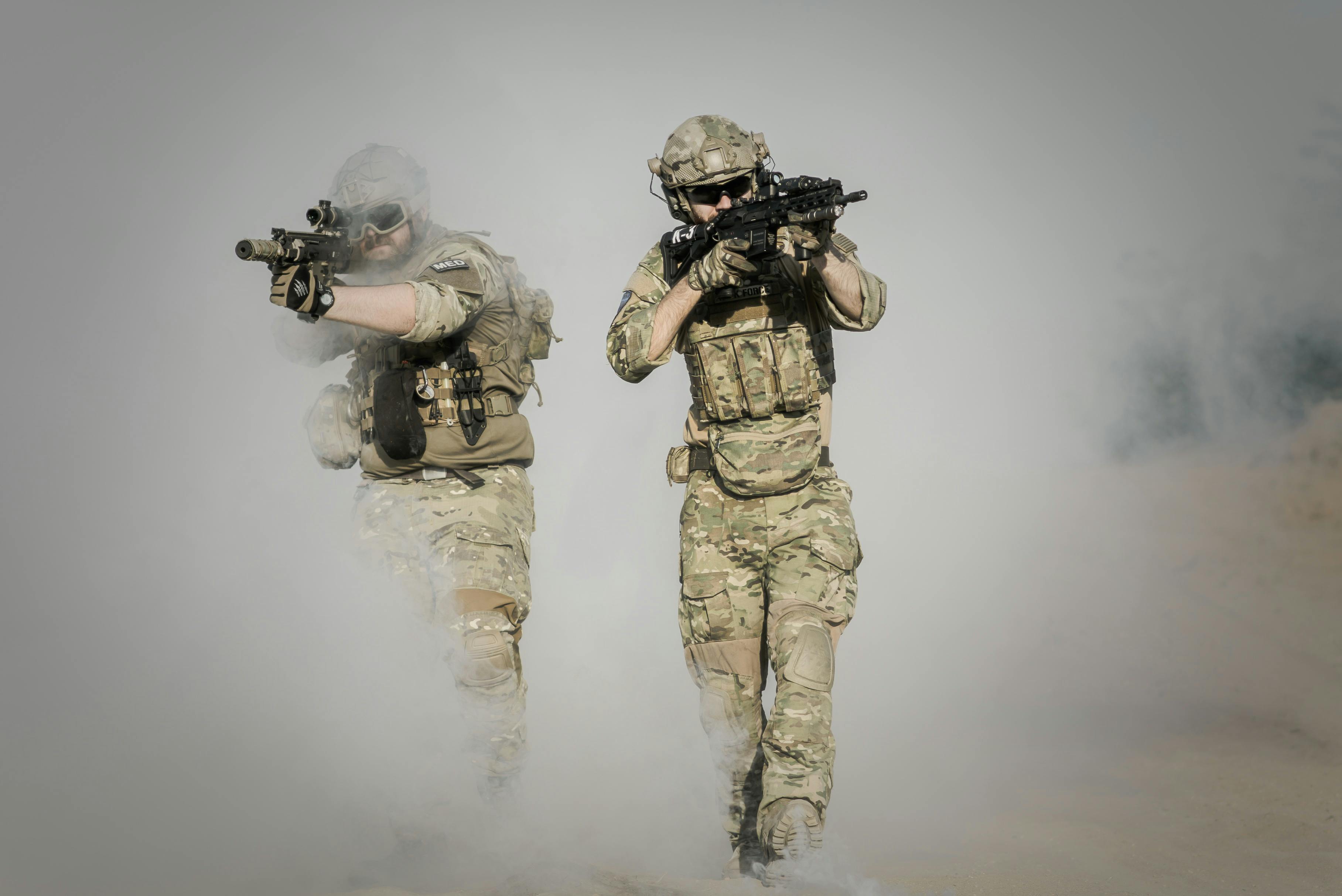 Two soldiers running with weapons in a thick white fog.