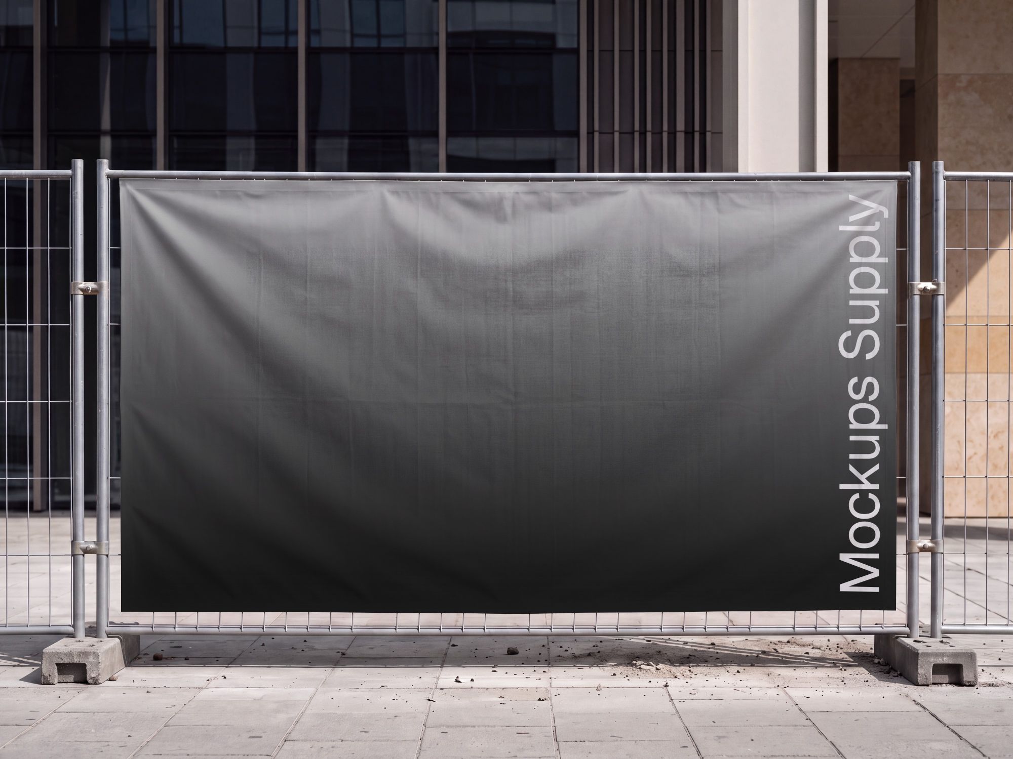 Large horizontal banner mockup stretched across a metal construction fence with concrete feet