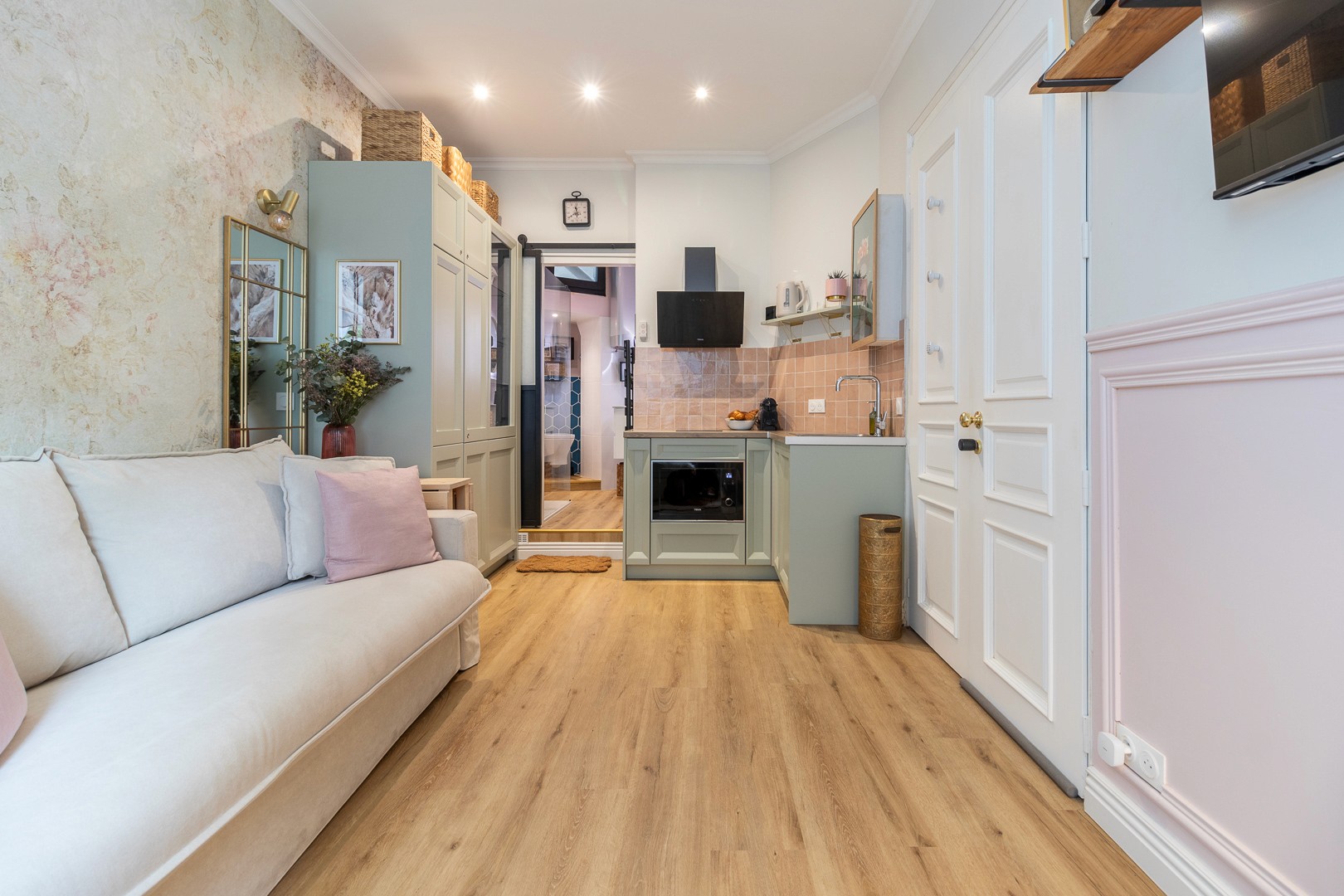 View along the studio from the sofa to the kitchen, with pale wood flooring