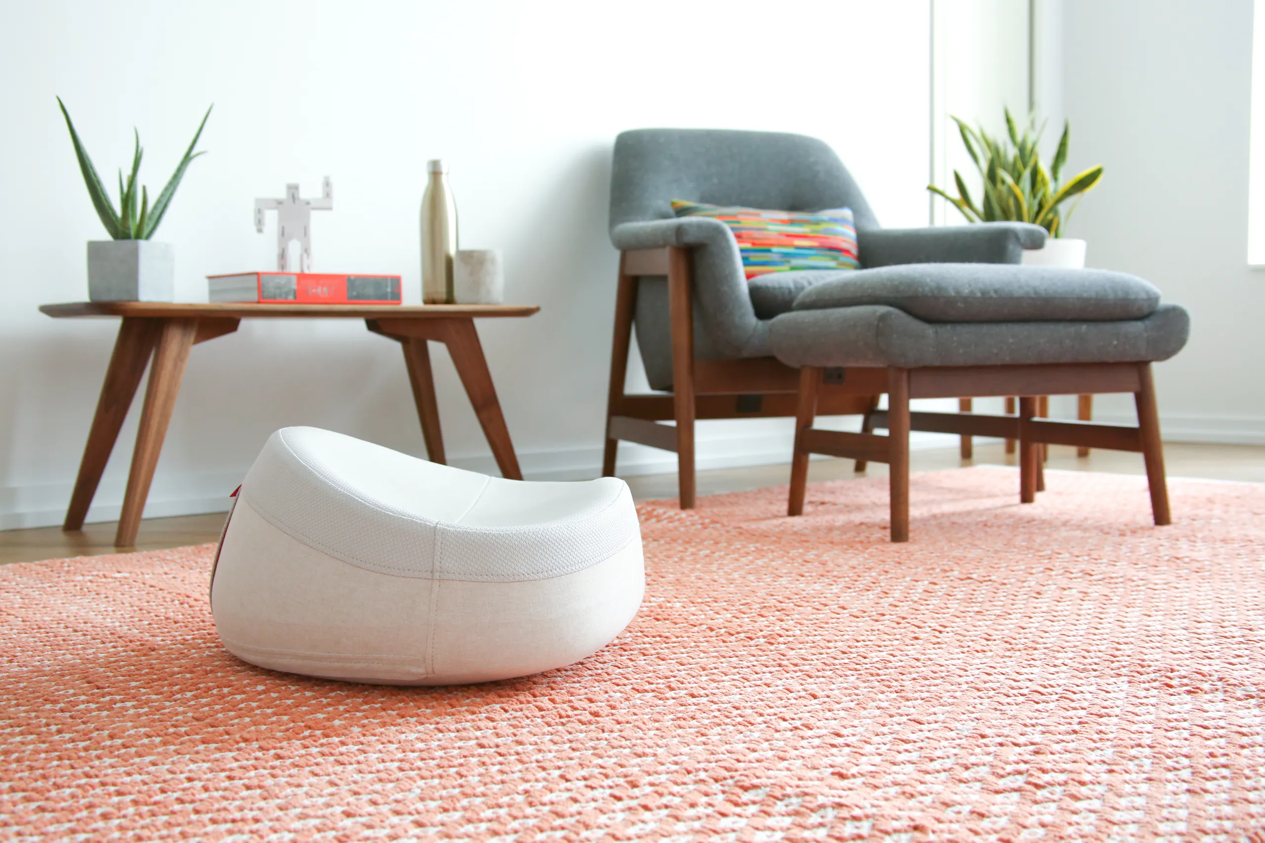 White UNDO meditation cushion in a modern living room with an orange rug