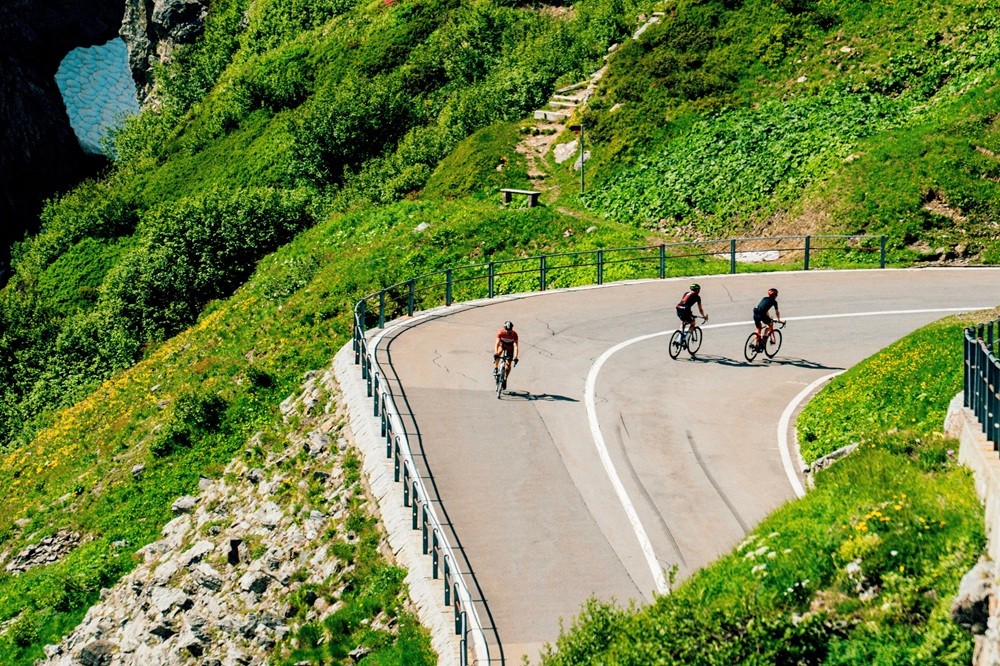 Trio of cyclists riding up a quiet mountain road in the Swiss Alps