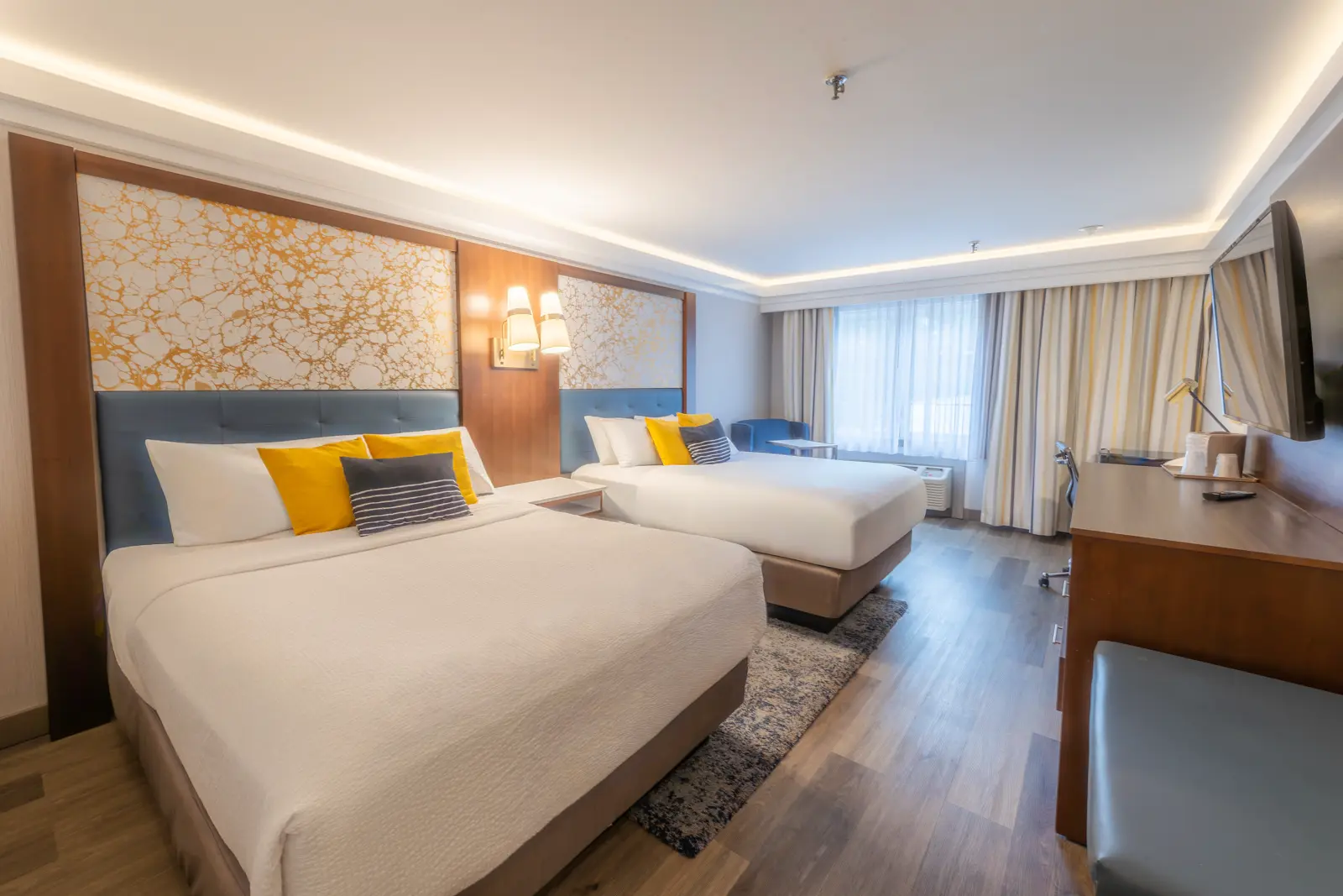 Hotel room with two beds, desk, and television.