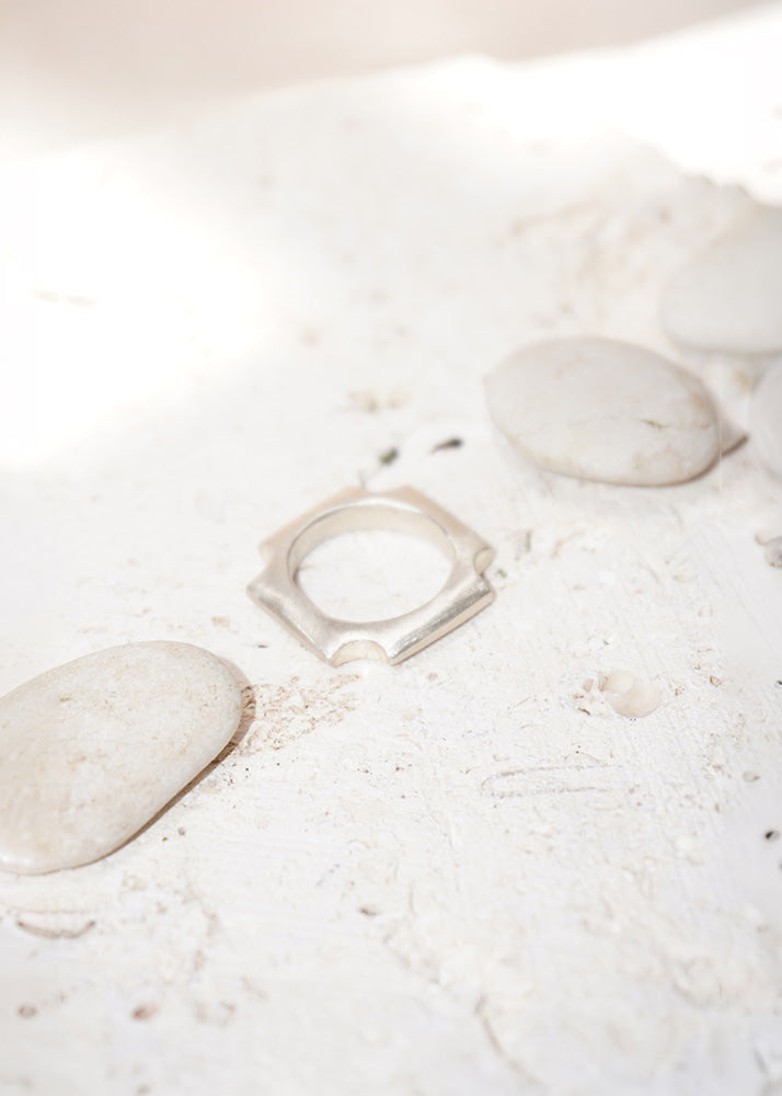 Silver ring on a white surface with stones