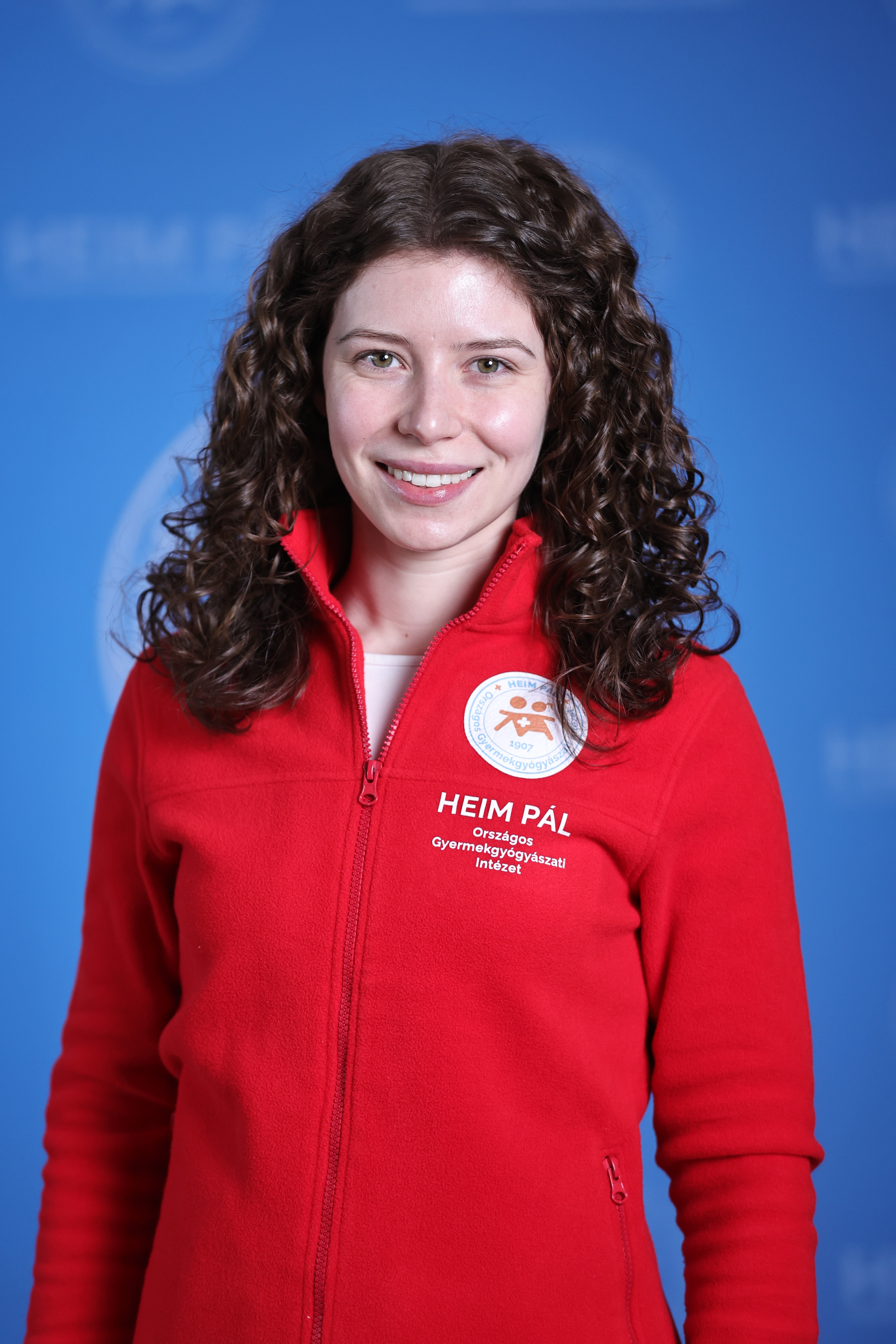 Hosszú barna göndörhajú nő piros kardigánban