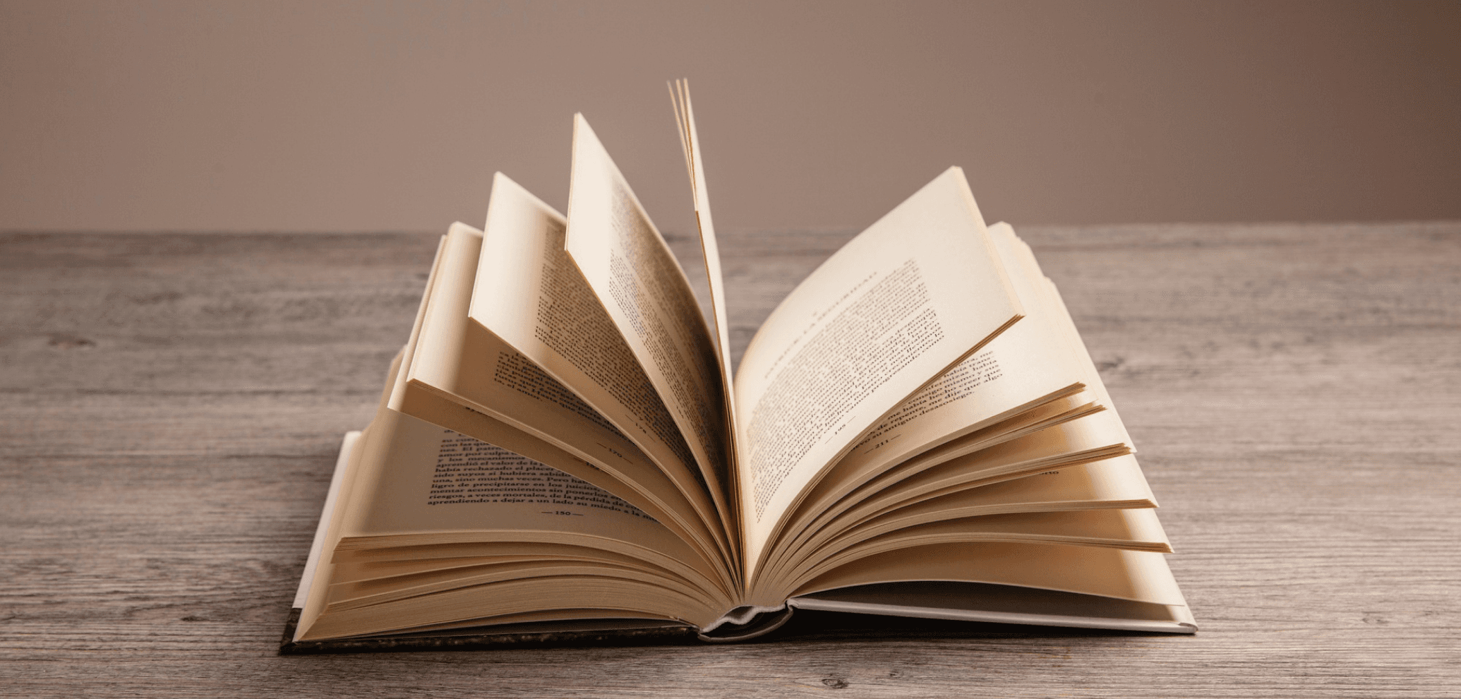 Open book with fanned-out pages on a wooden table.