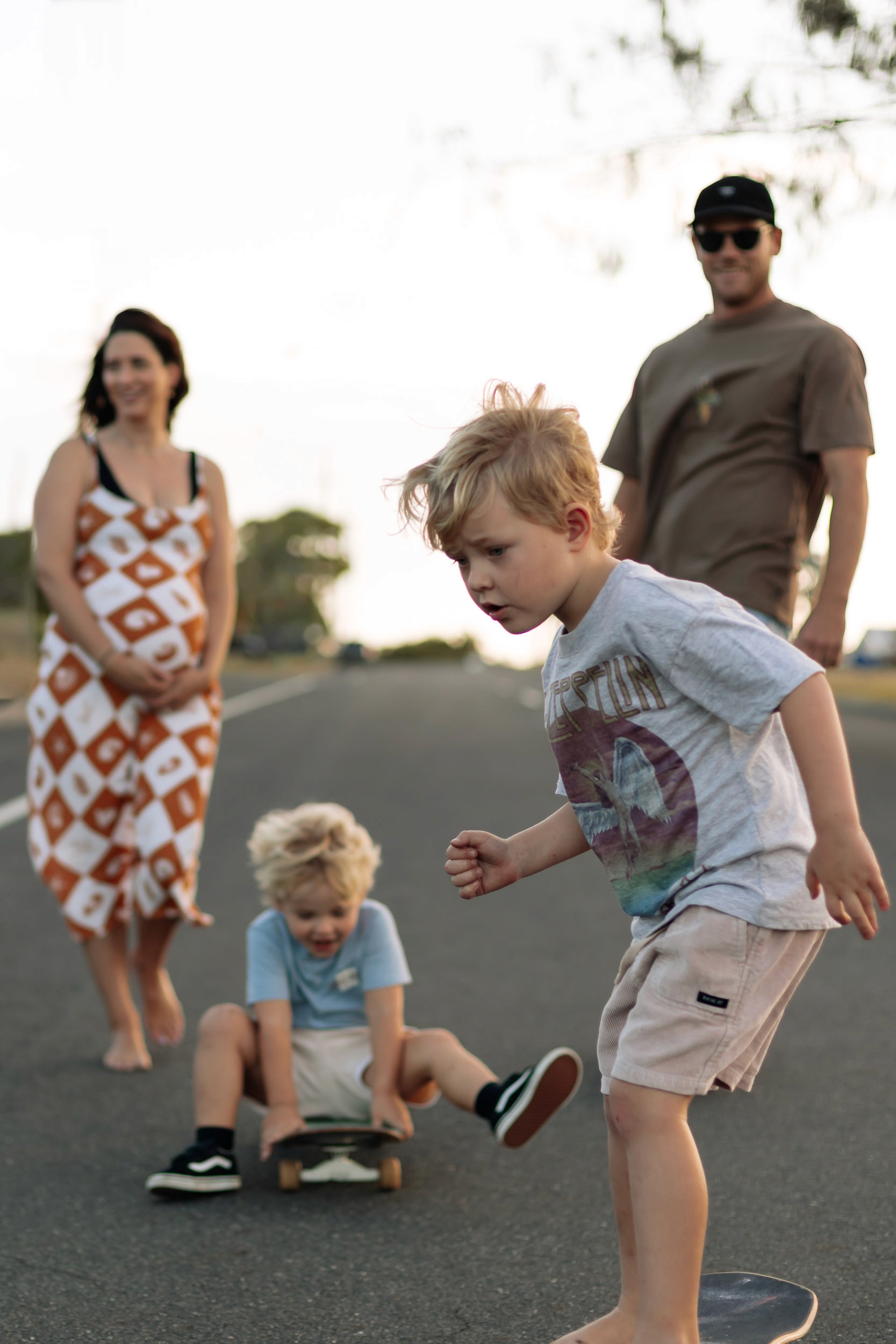 Family of four skateboarding together along an open road during a fun and adventurous Mackay family photography session.
