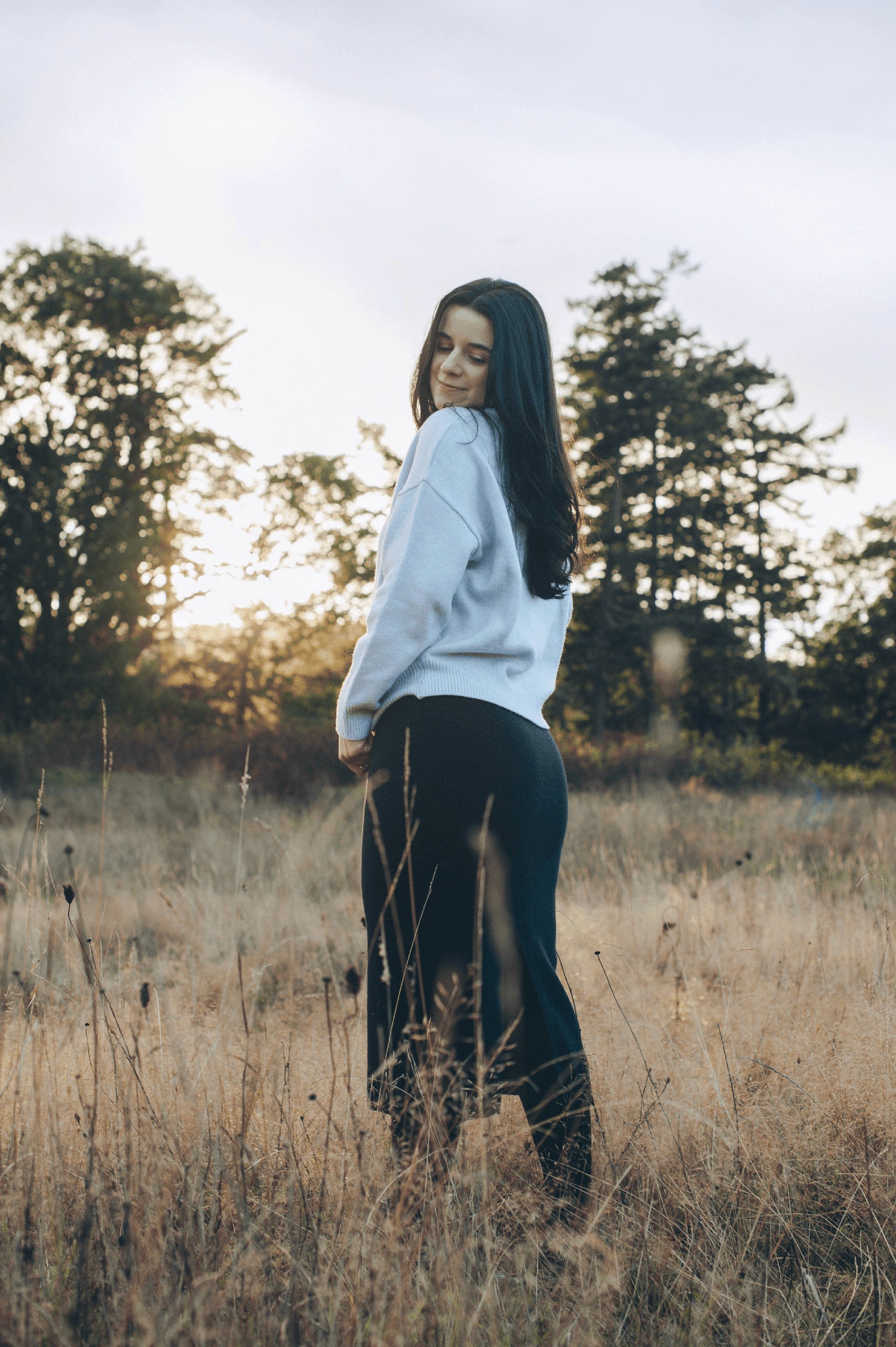  field (middle left)Woman in a white jacket standing in a golden field at sunset, looking away from camera