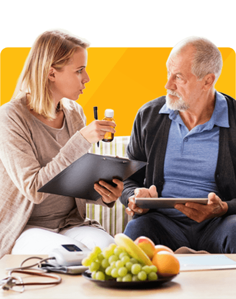 A woman and an older man engage in conversation, surrounded by food on a table. They appear thoughtful.