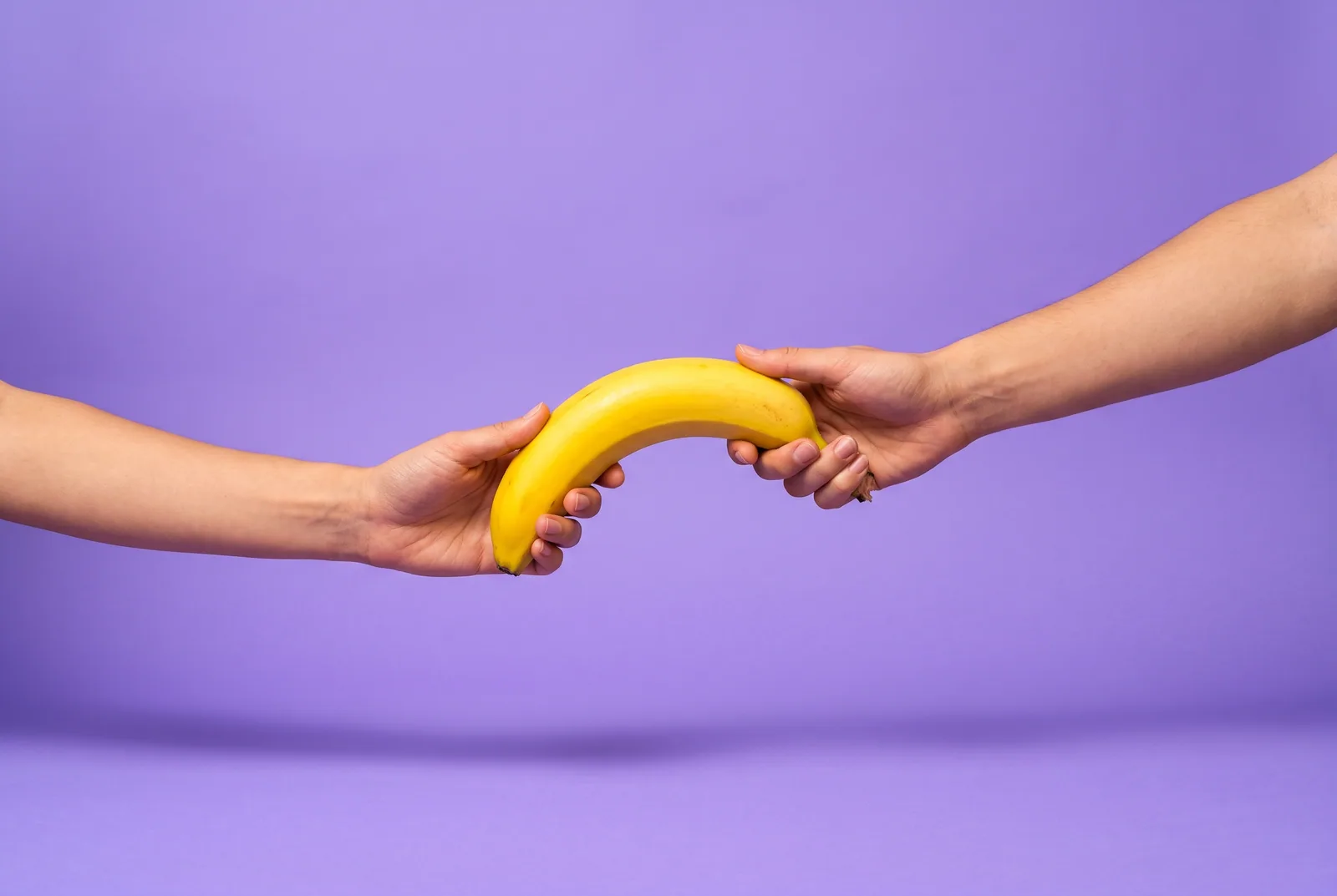 Two hands passing a banana like a relay baton, a playful QUITTR vs Relay comparison