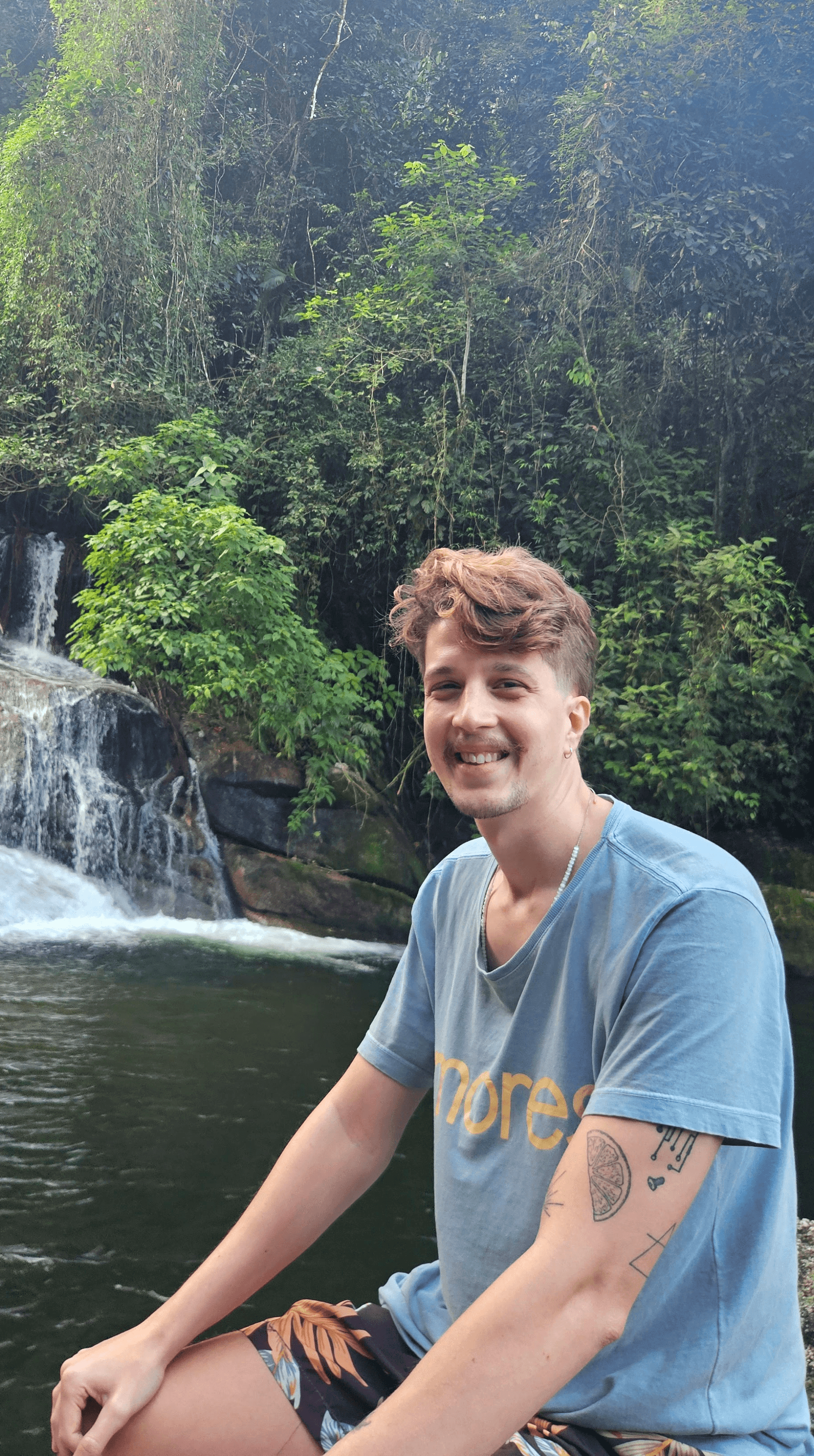 Leonardo sentado na pedra em uma cachoeira em momento de descontração