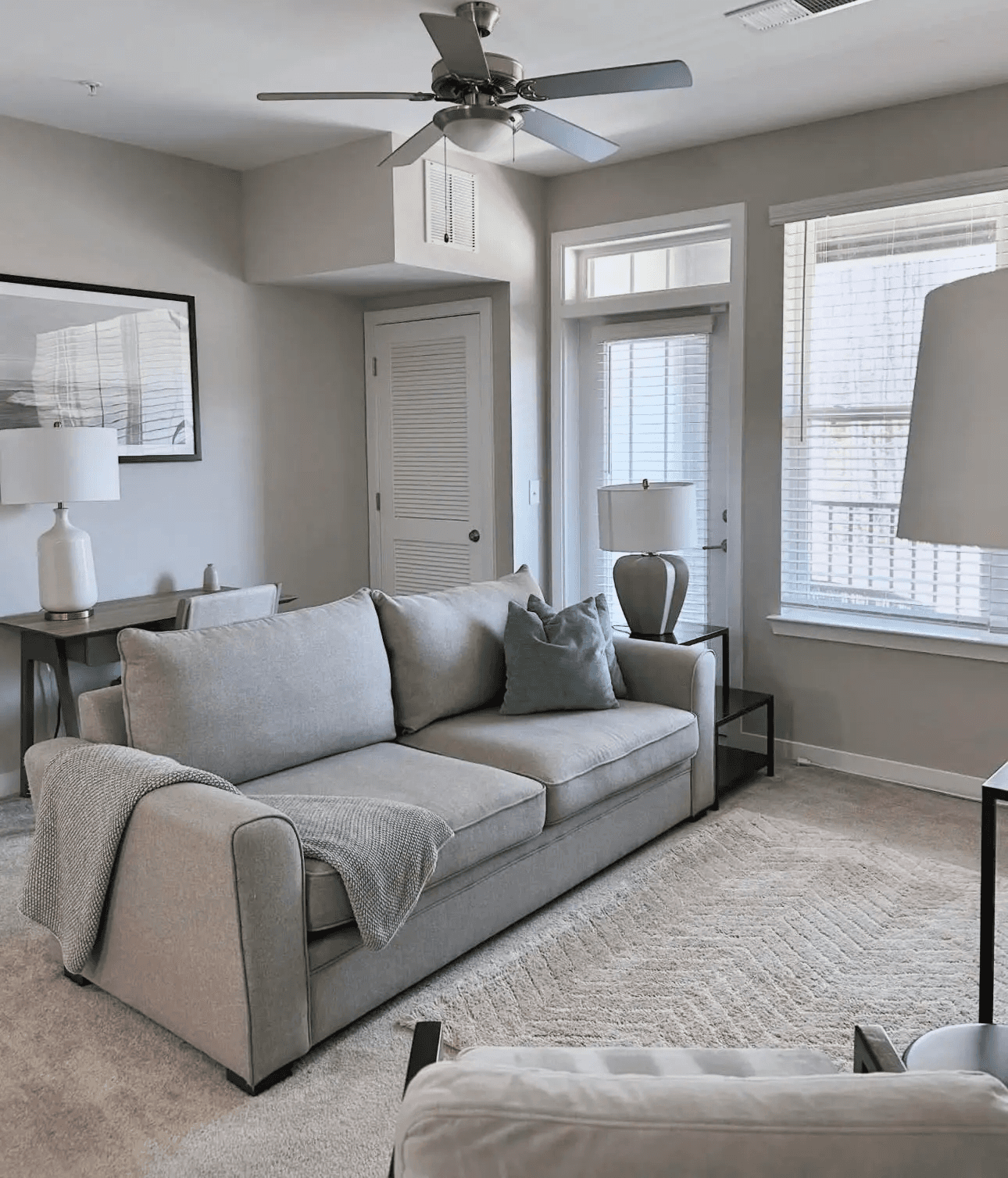 Professionally cleaned Airbnb living room with vacuumed carpets, staged pillows, and a tidy desk area for rental turnover services.