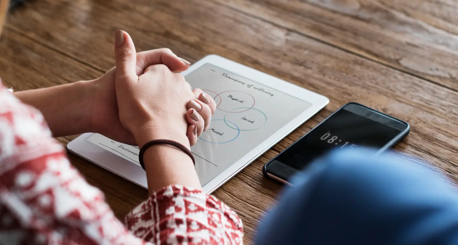 Smiling man in a blue beanie and black hoodie against a brick wall, exuding a joyful and relaxed vibe.