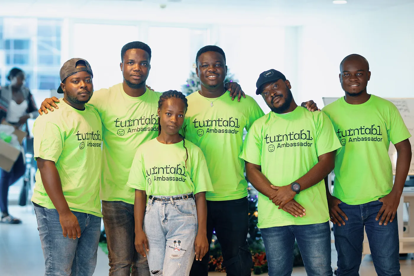 A group of Turntabl alumni smiling and posing for a group photo in matching green Turntabl t-shirts.