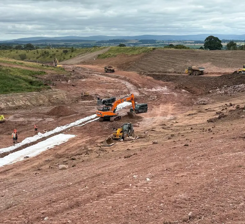 Excavators and dump trucks carrying out bulk earthworks and drainage installation on a large-scale civil engineering infrastructure project.