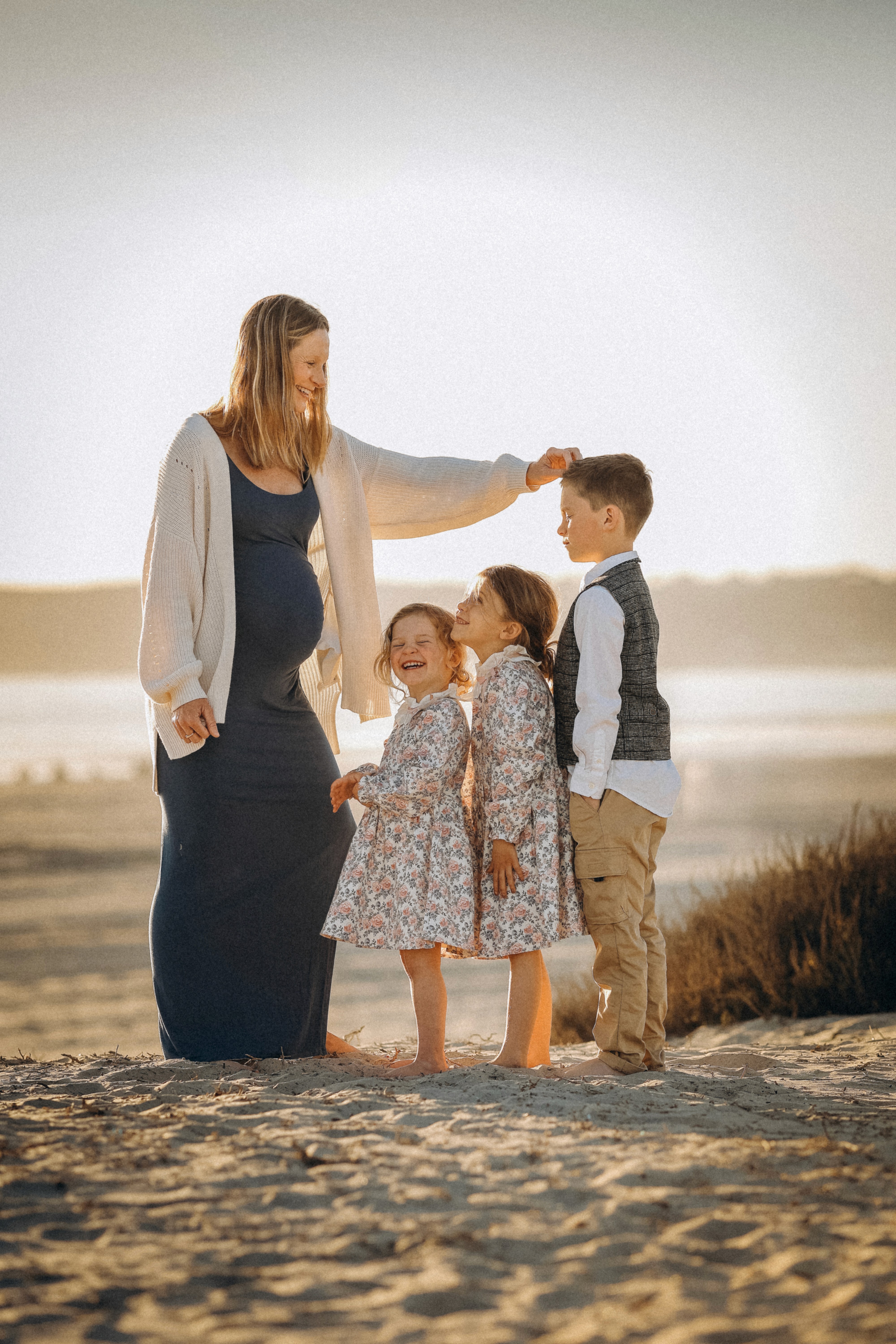 Family standing together in soft coastal light during a beach session in Oceanside