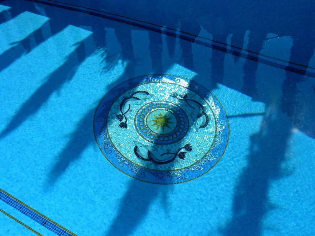 Hand-cut mosaic medallion set into a swimming pool floor, seen through the water — Mosaiclegs Art Studio
