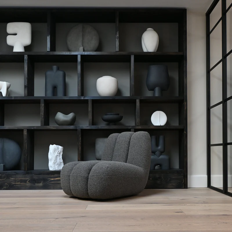 Minimalist workspace with natural stone columns, Scandinavian-style furniture, golden light, and greenery.