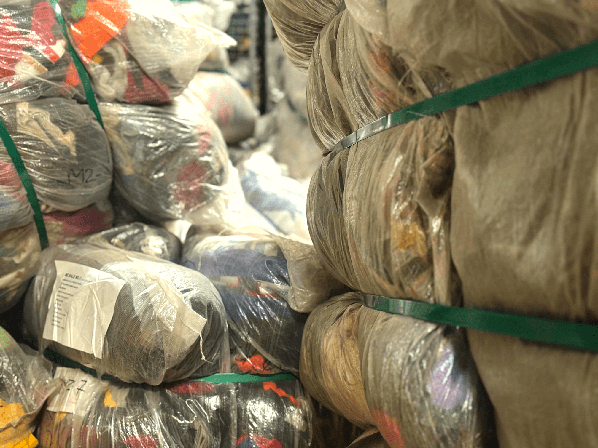 Bundles of used clothes wrapped in plastic and secured with green straps.