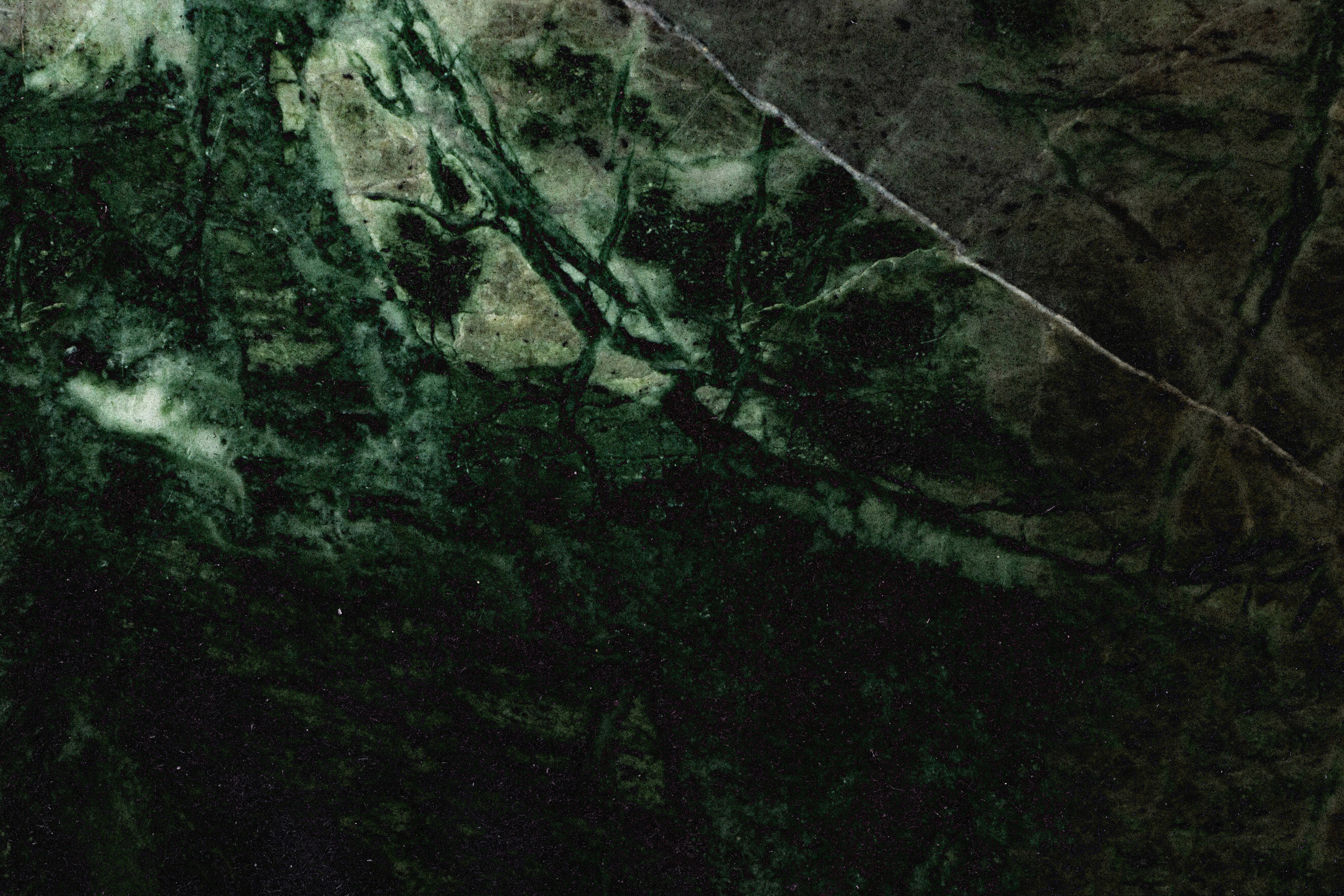 Close-up of a woman showcasing ornate gold jewelry, including chunky rings with red gemstones, a layered necklace, and butterfly earrings, under warm, shadowed lighting.