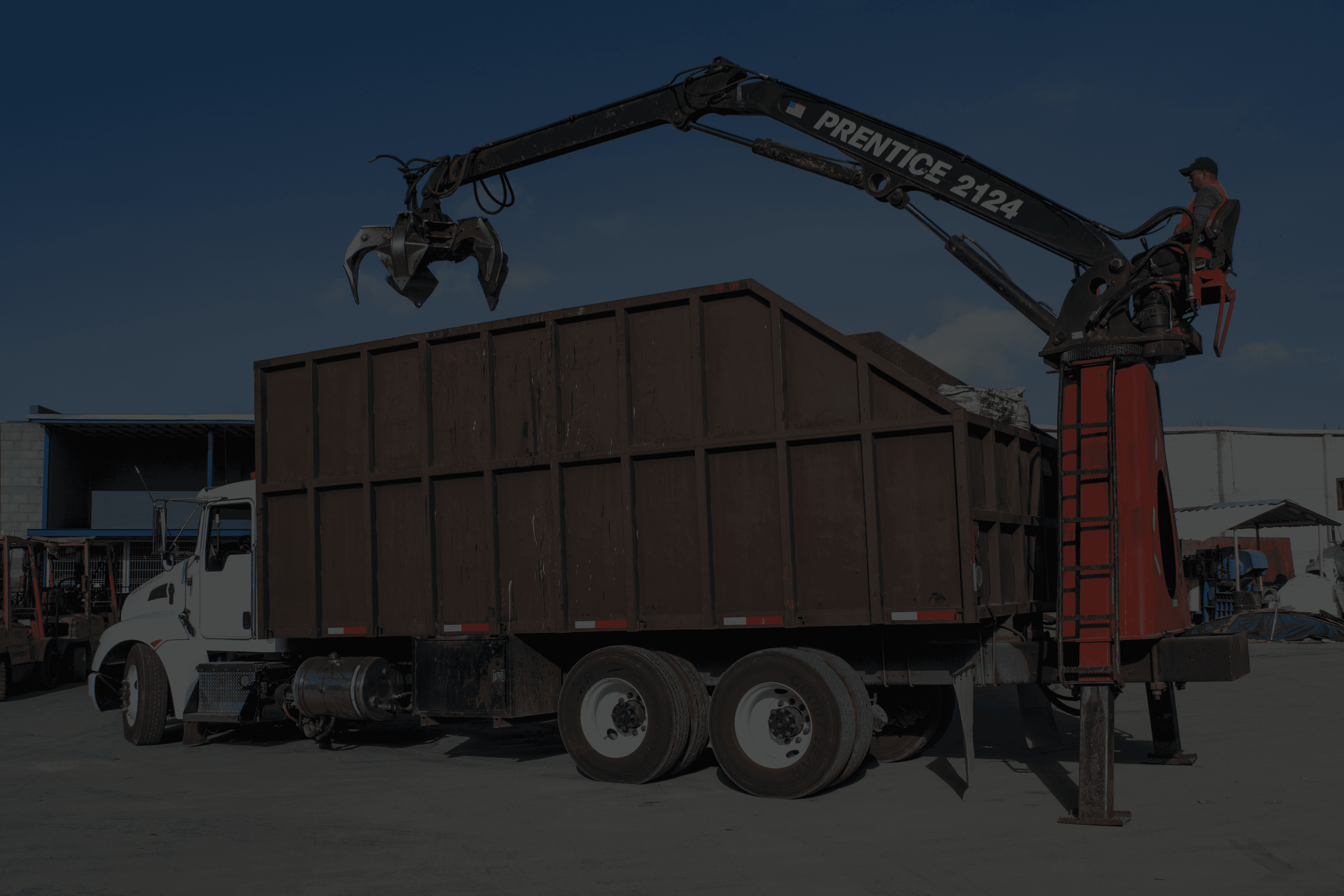 Crane truck loading debris into a large bin.