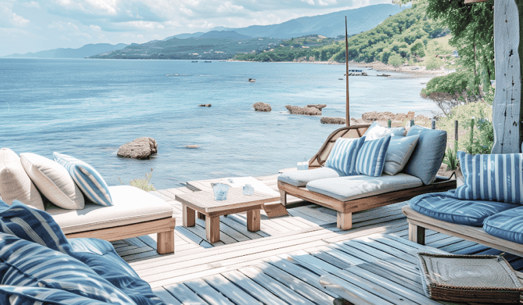 Coastal deck with blue-striped lounge seating overlooking the sea and rocky shore.