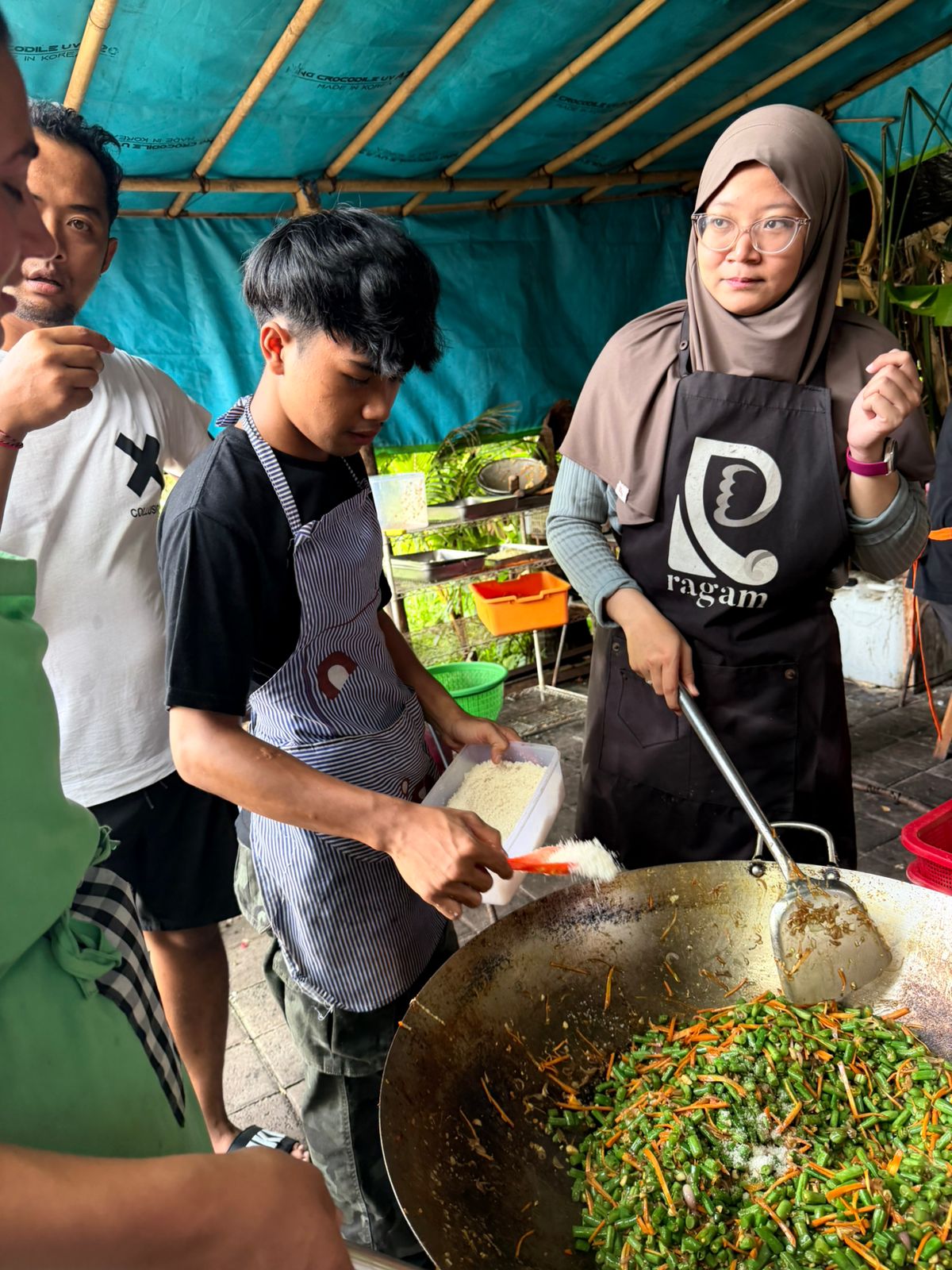 Volunteer mentor helps a young Indonesian trainee put on his apron at the Ragam culinary training program in Bali.