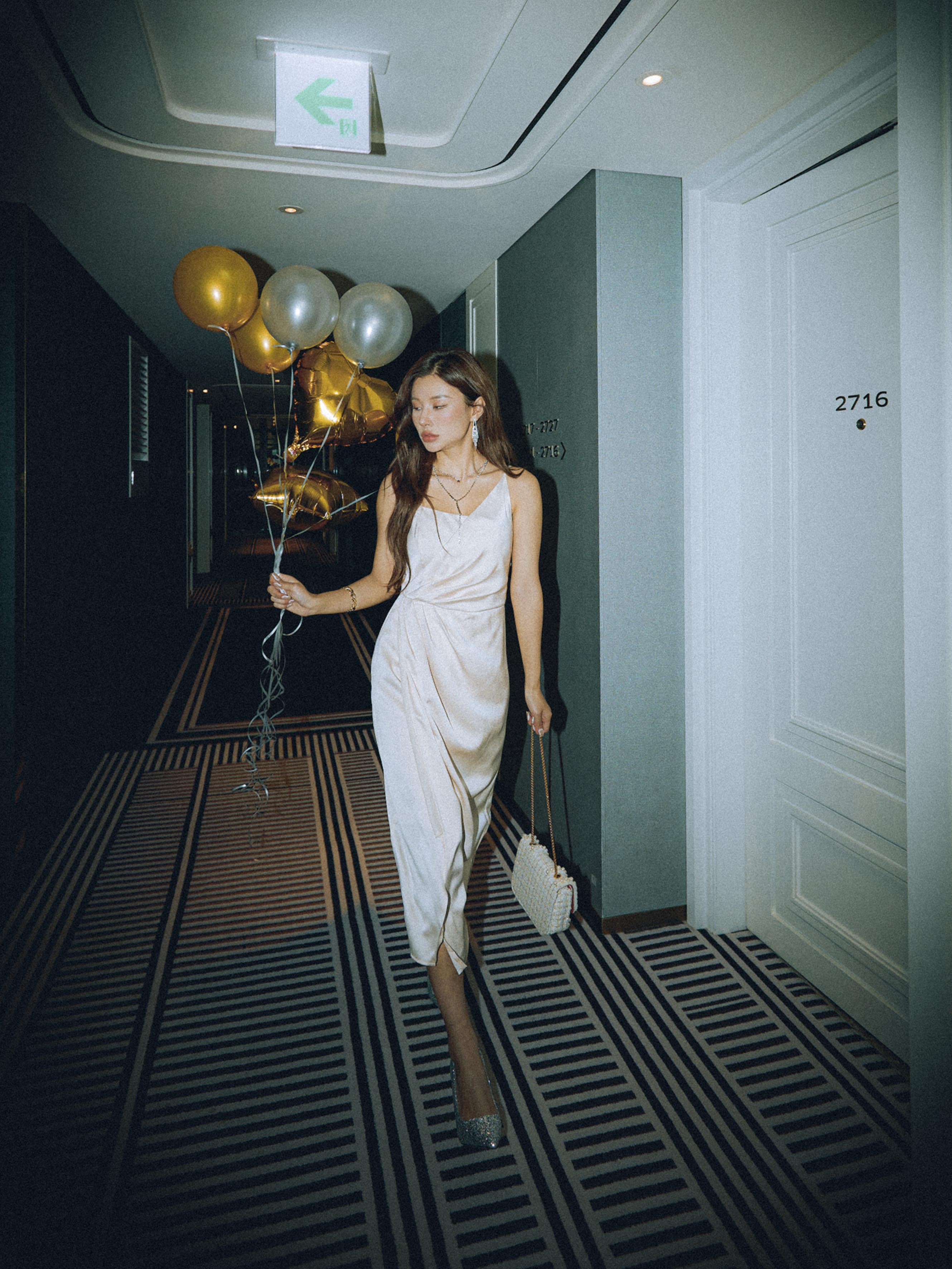 "Elegant in a satin slip dress, holding balloons for a chic celebration."