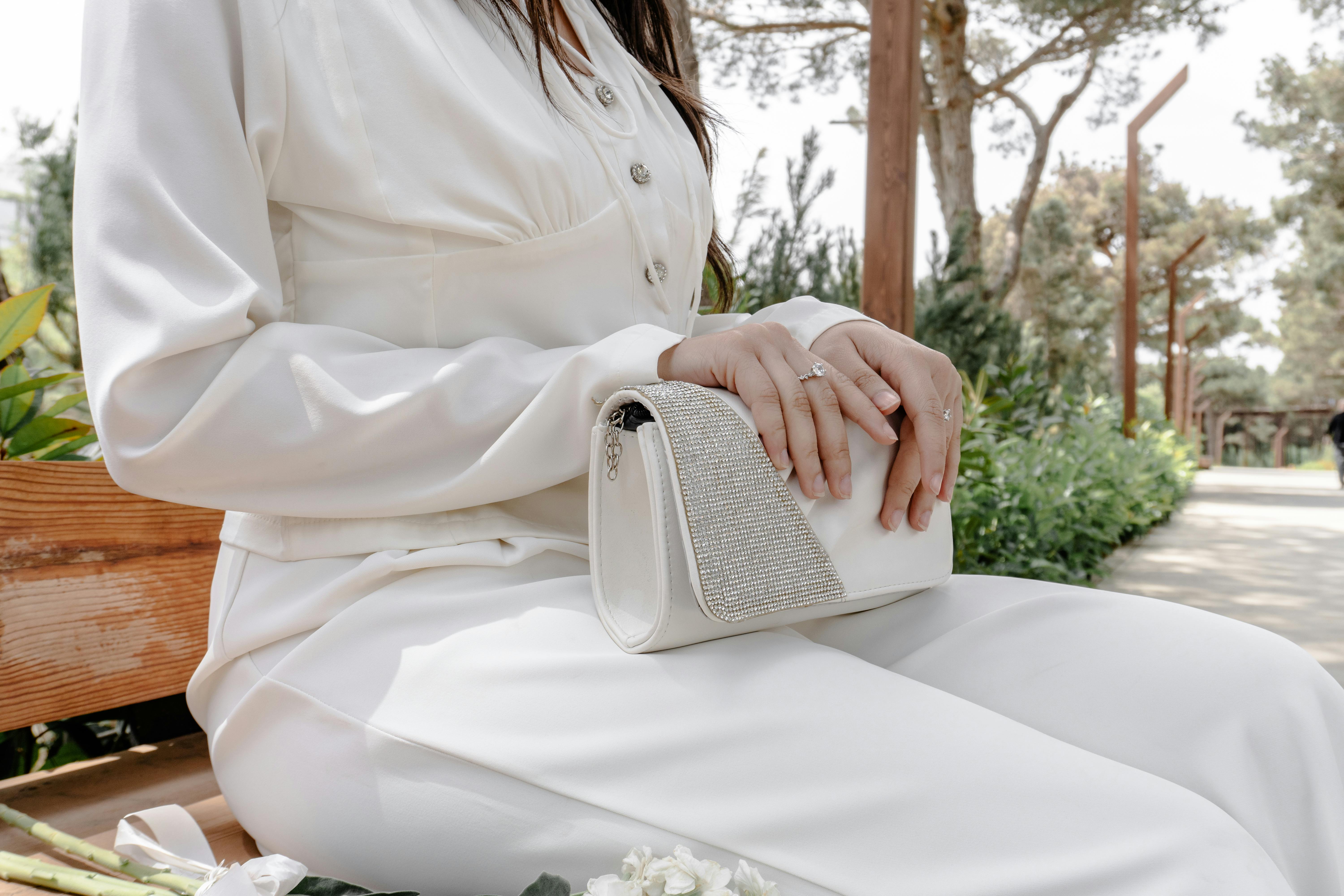 woman holding a white luxury purse outside