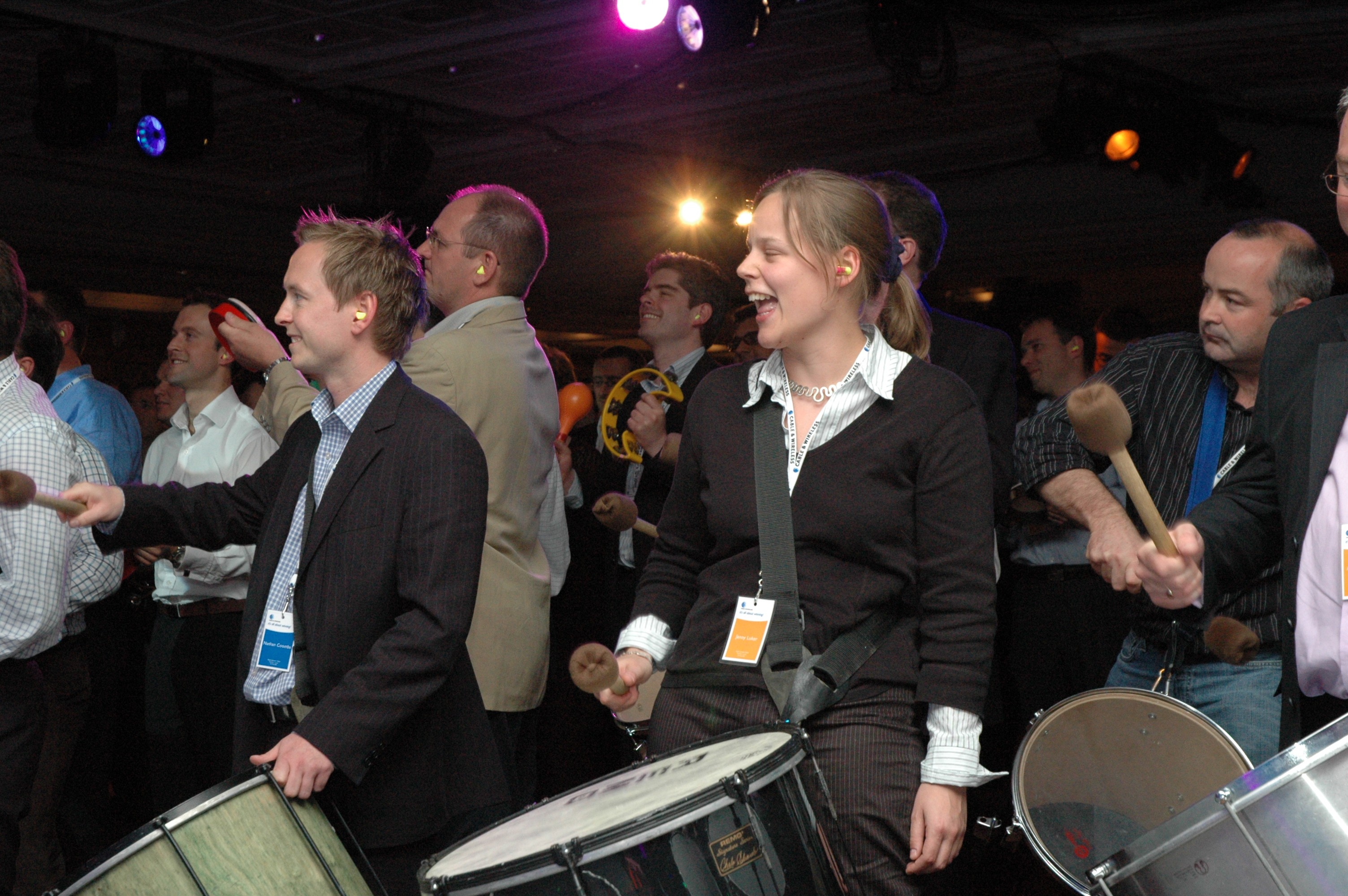 Corporate guests taking part in a drumming workshop, playing percussion instruments together.